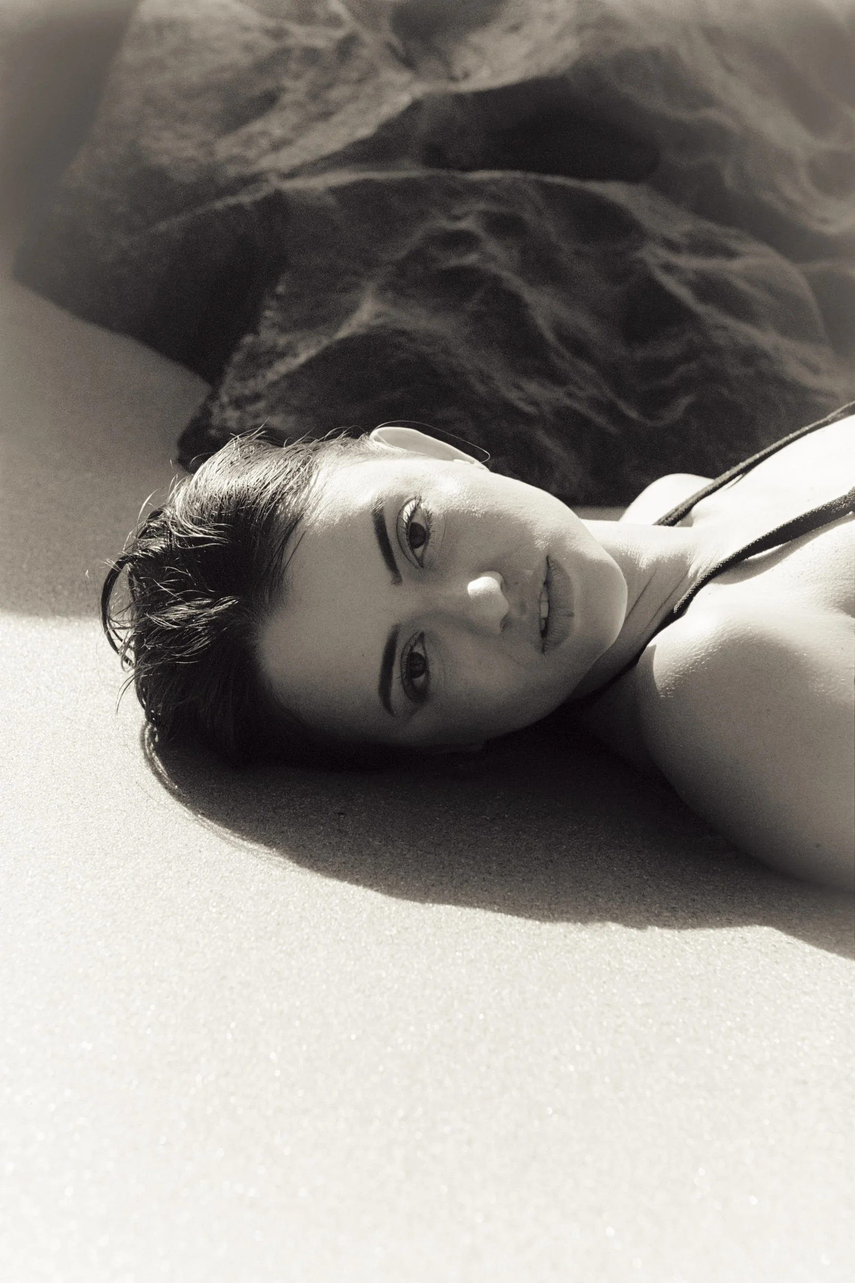 Lying on the sand, gaze straight to camera, black and white, 35mm film