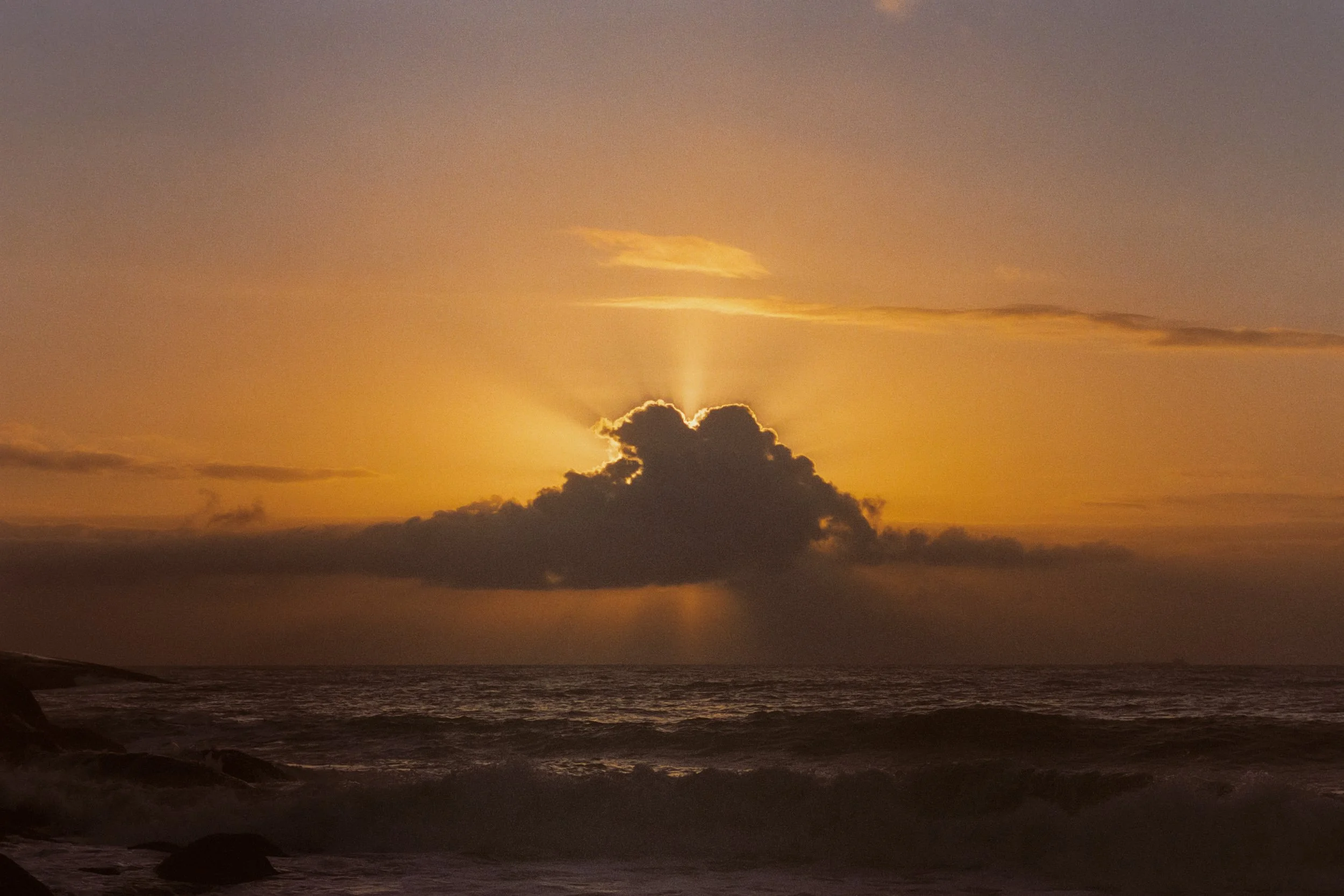 Sun breaking behind a single cloud over the open sea, 35mm film