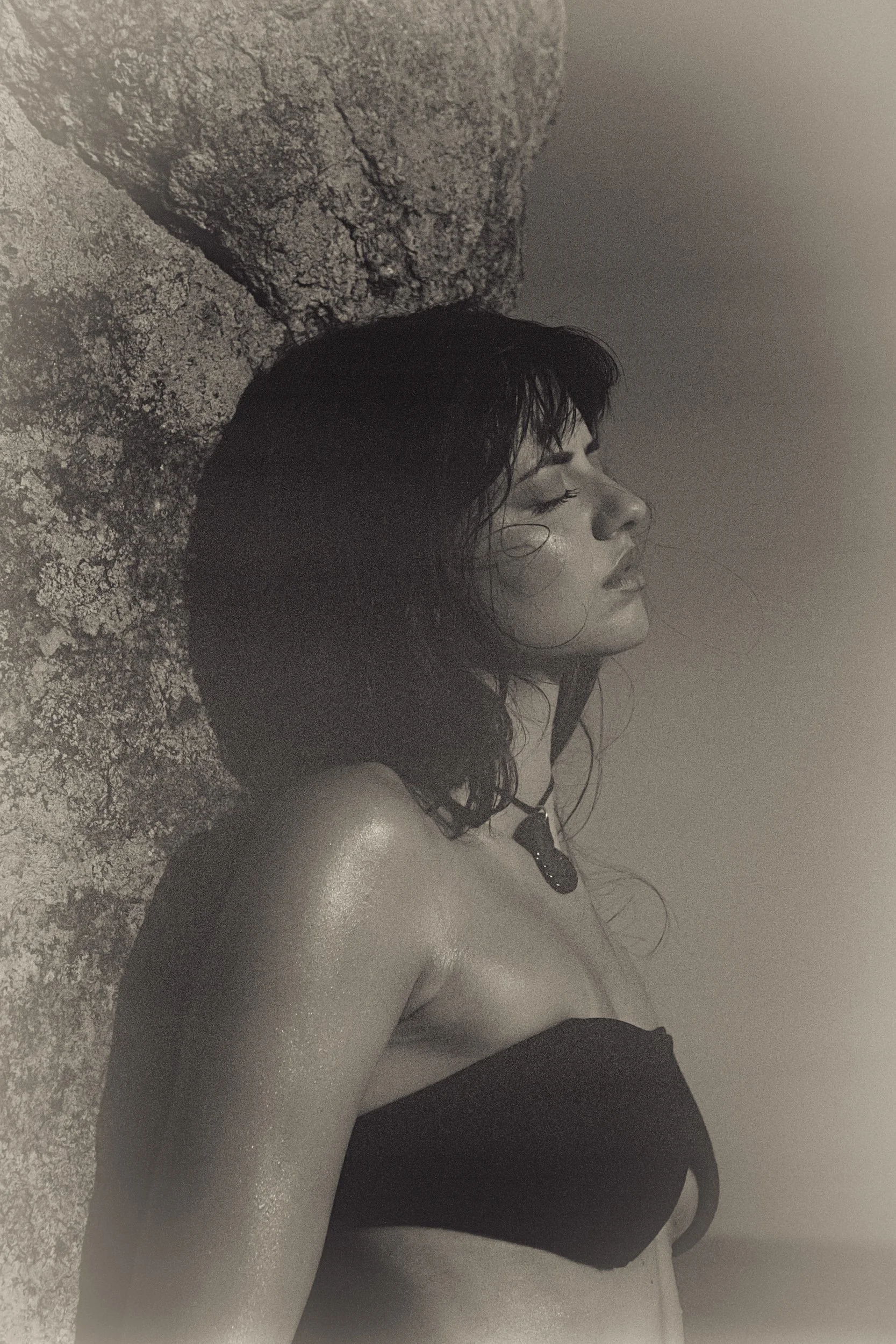 Model in profile against lichen-covered rock, black bandeau top, 35mm film