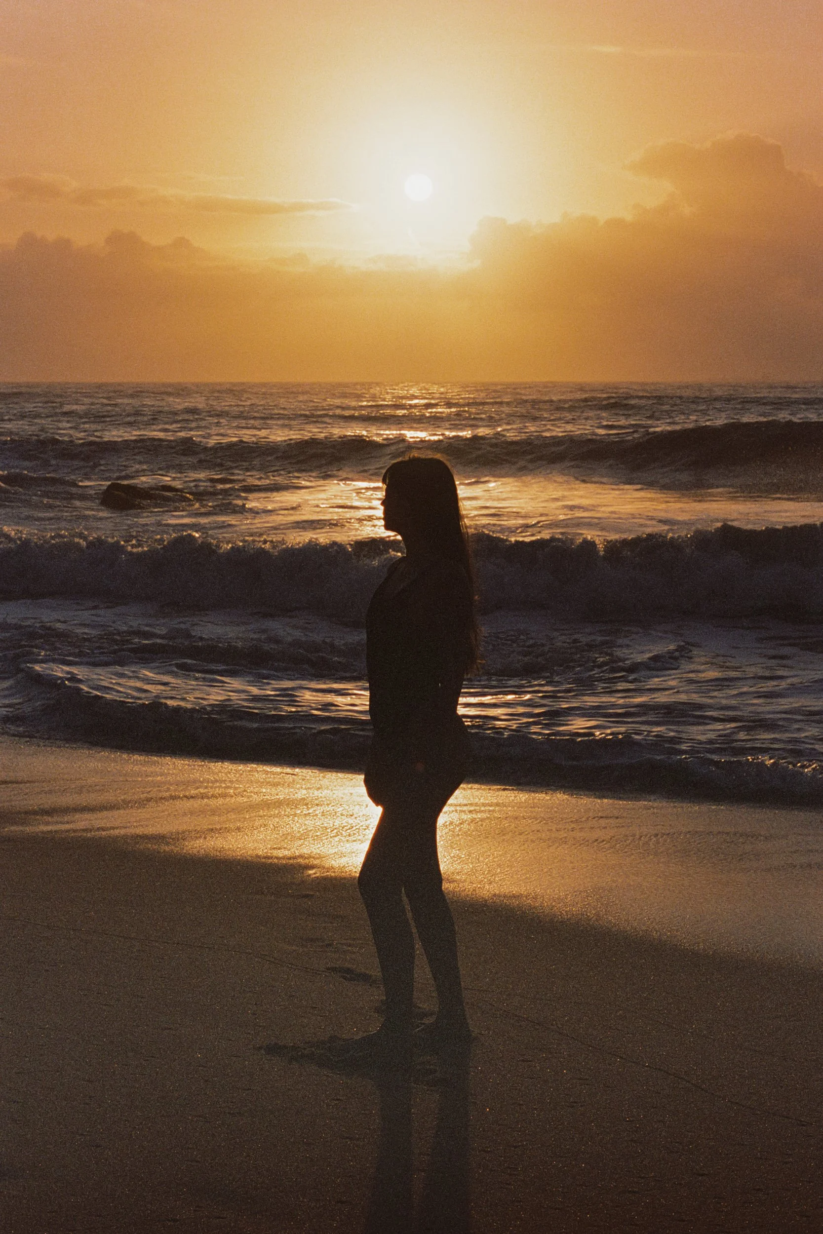 Silhouetted at the shoreline facing the low sun, 35mm film