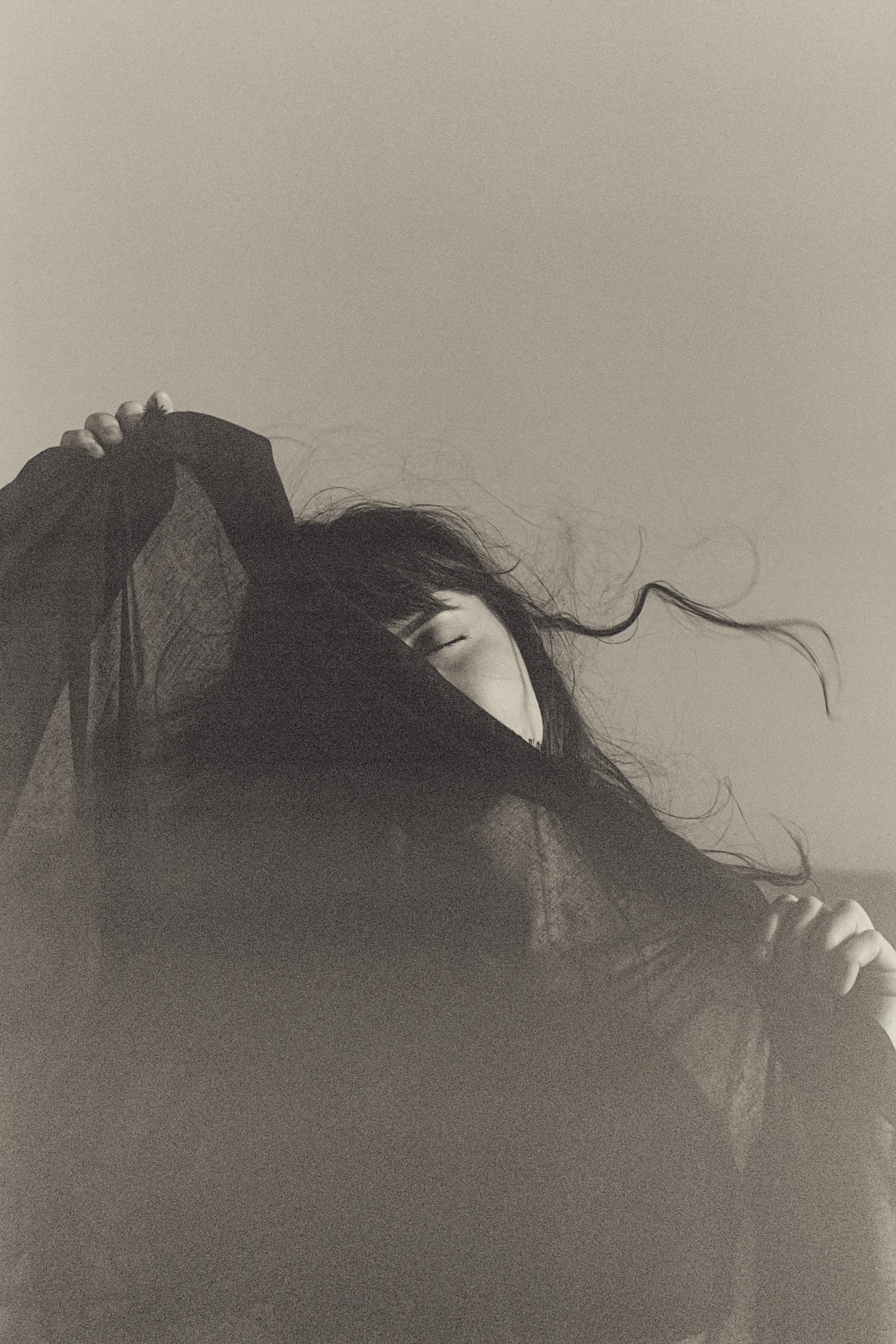 Hair lifted in the wind, face half hidden, black and white, 35mm film
