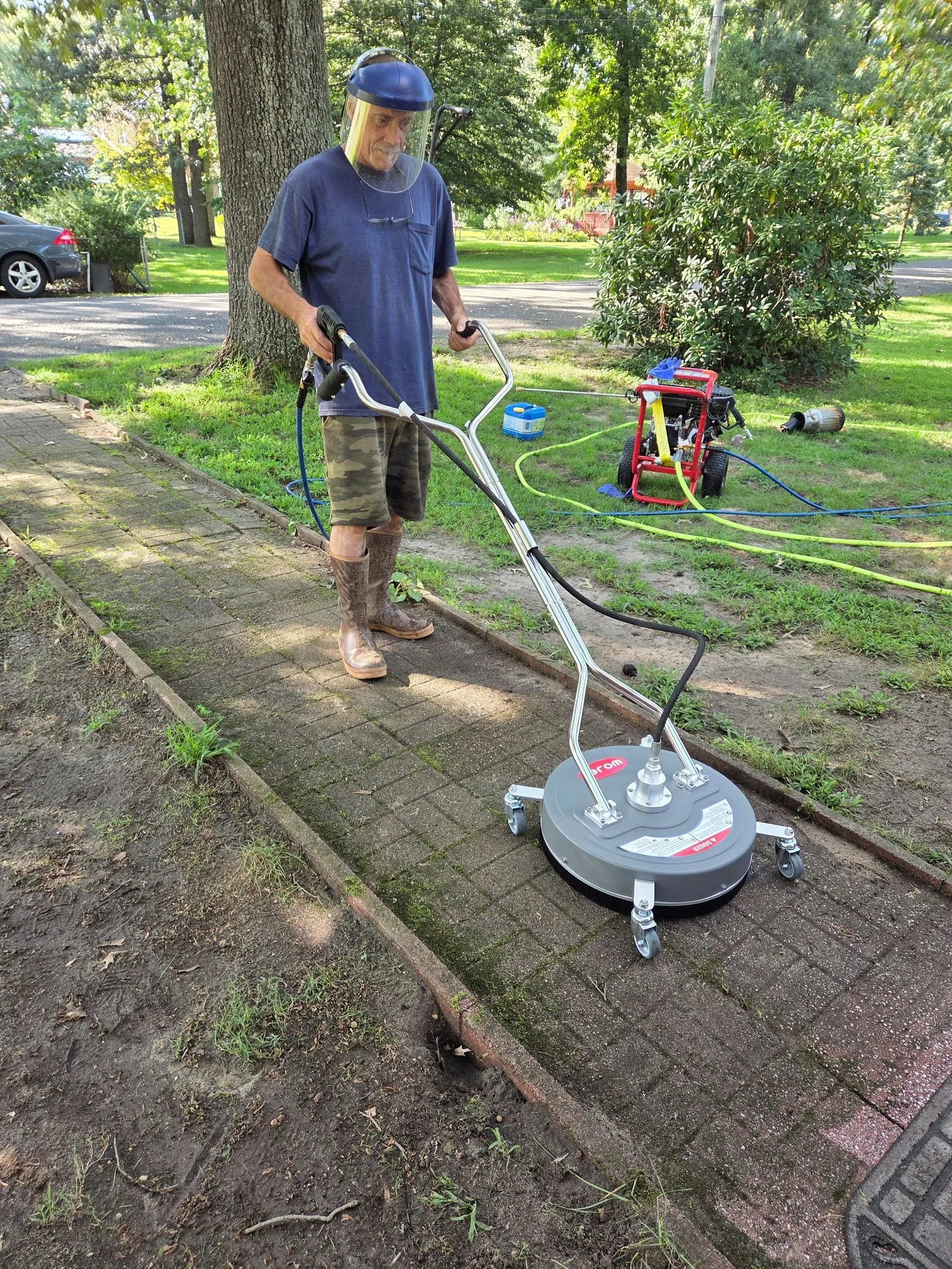 Owner Mike surface cleaning moss‑covered walkway using professional equipment during soft‑wash treatment