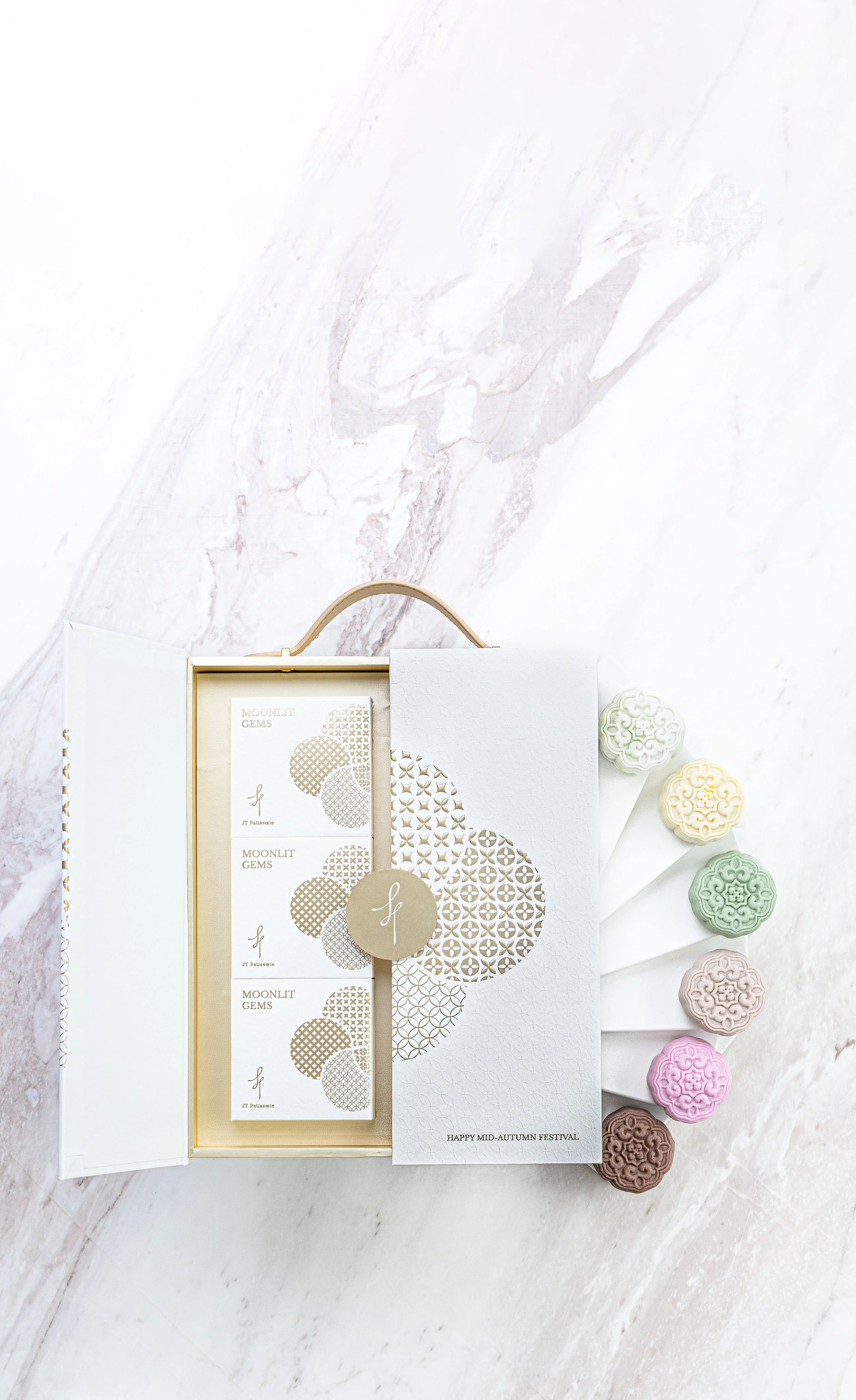 A decorative box of moonlit gemstone candies in pastel colors includes pink, green, yellow, purple, brown, and white, arranged on a white marble surface with a Mid-Autumn Festival message.
