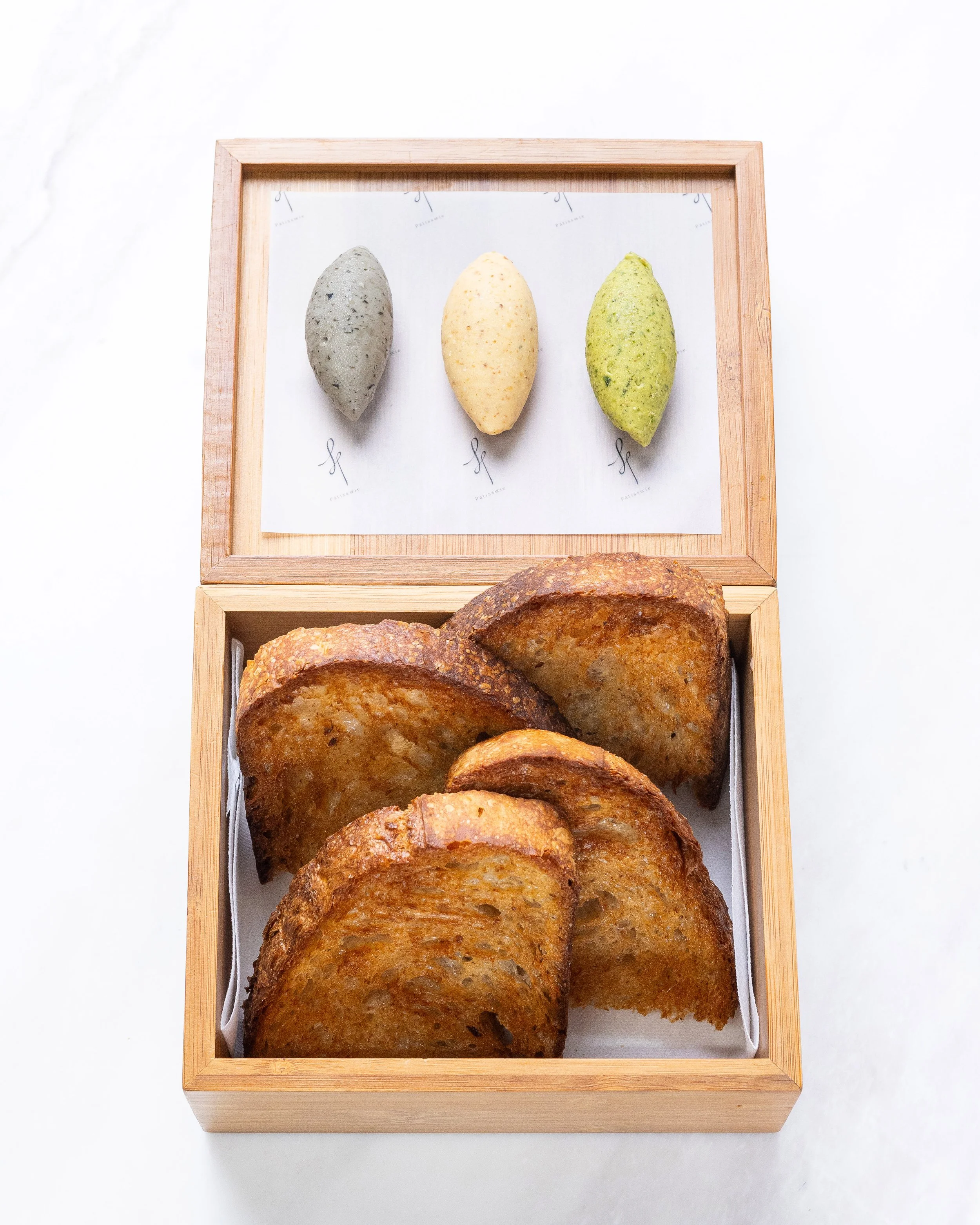 A wooden box with slices of toasted bread inside on a white surface.