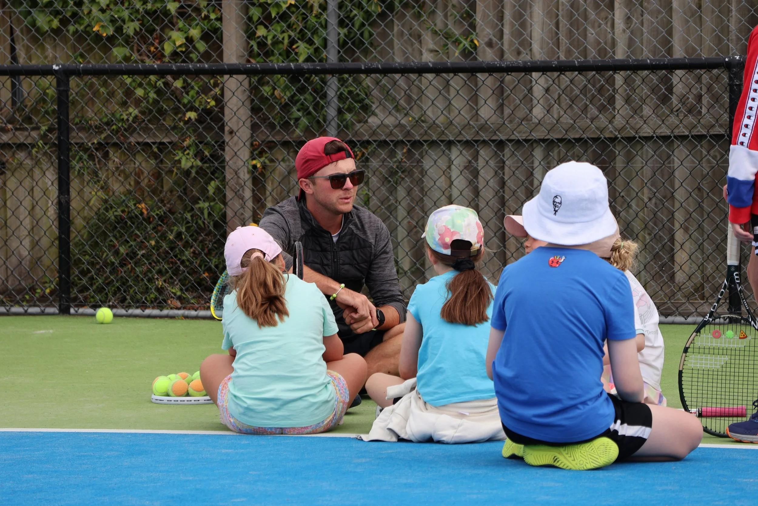 Tennis coach working with children on an outdoor court in Christchurch