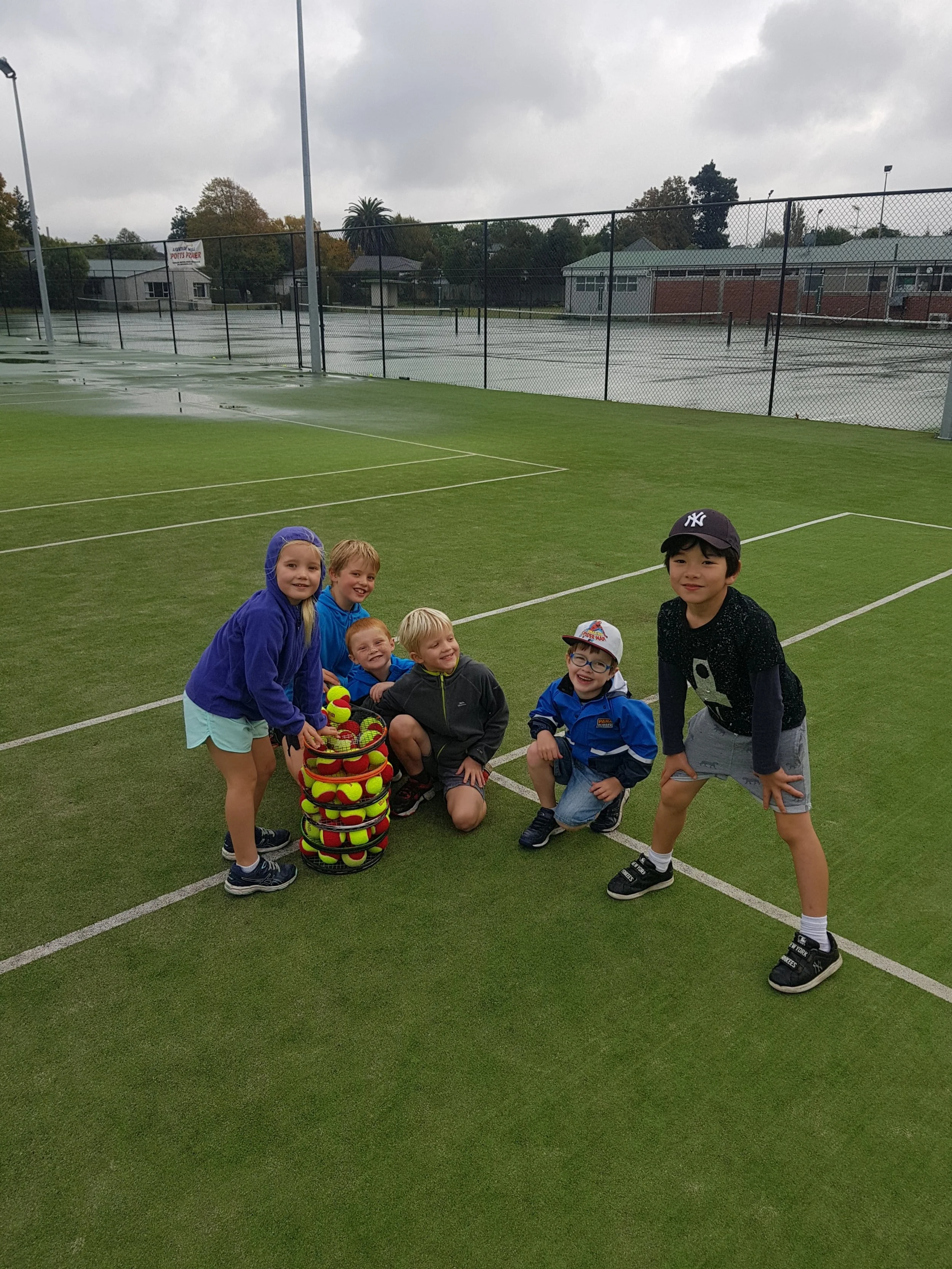 Children learning tennis skills with a coach on court