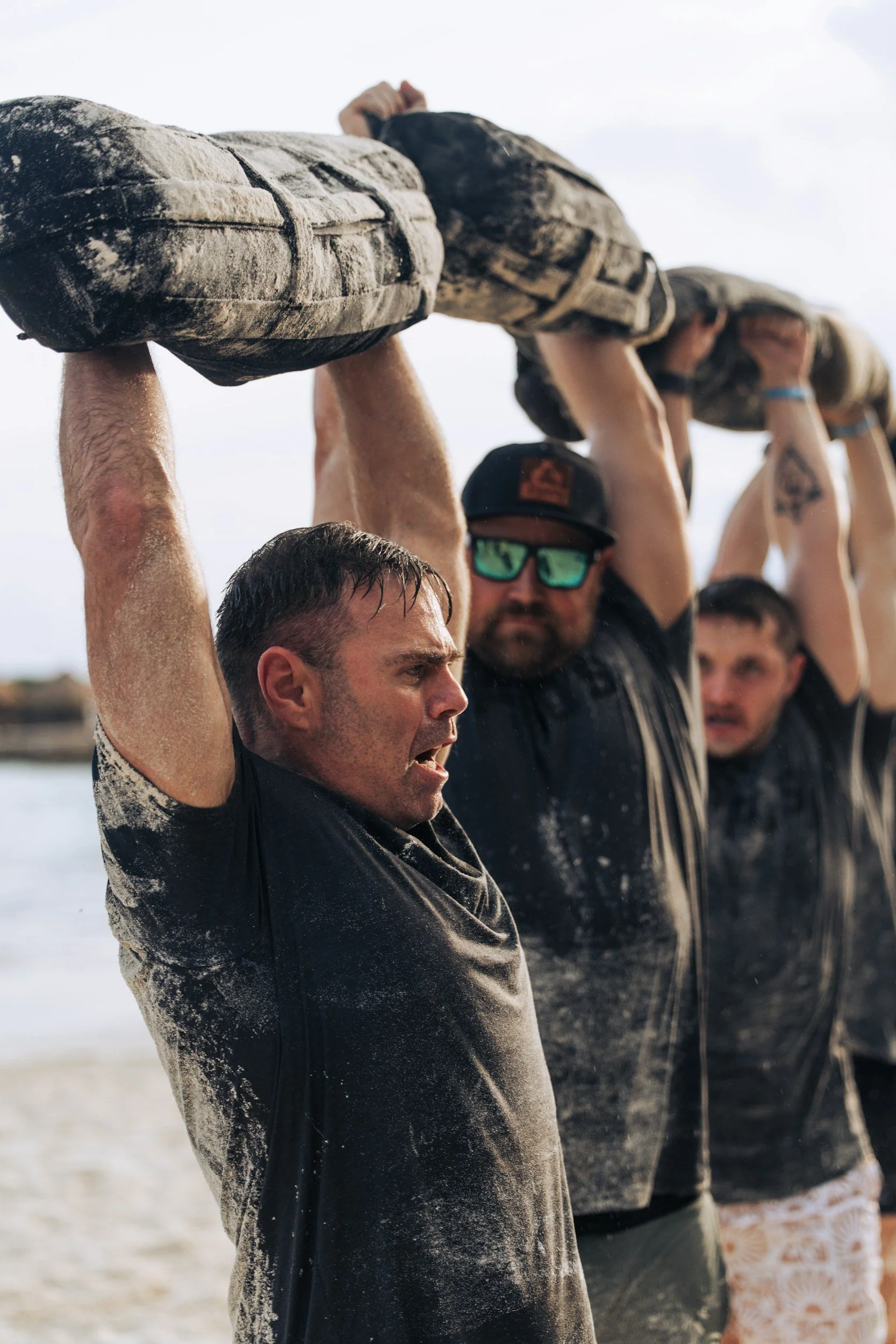 Team carrying logs overhead during an outdoor strength and team building workout.
