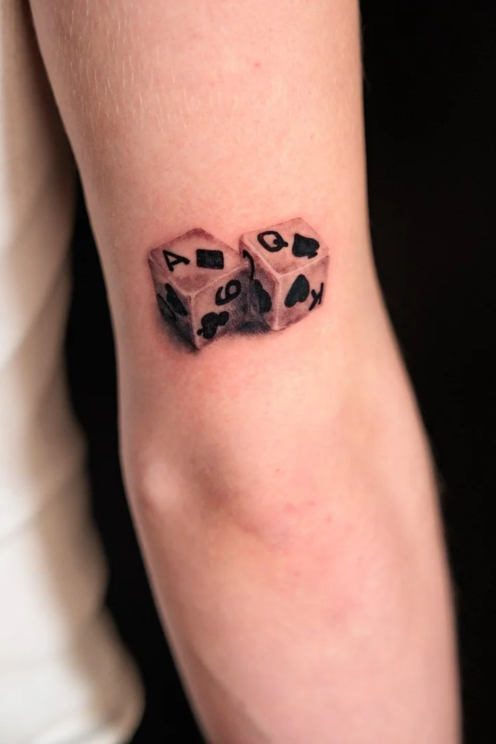 Tattoo of two six-sided dice showing the numbers four, six, nine, and ten.