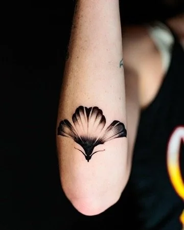 Tattoo of a butterfly on a person's upper arm.