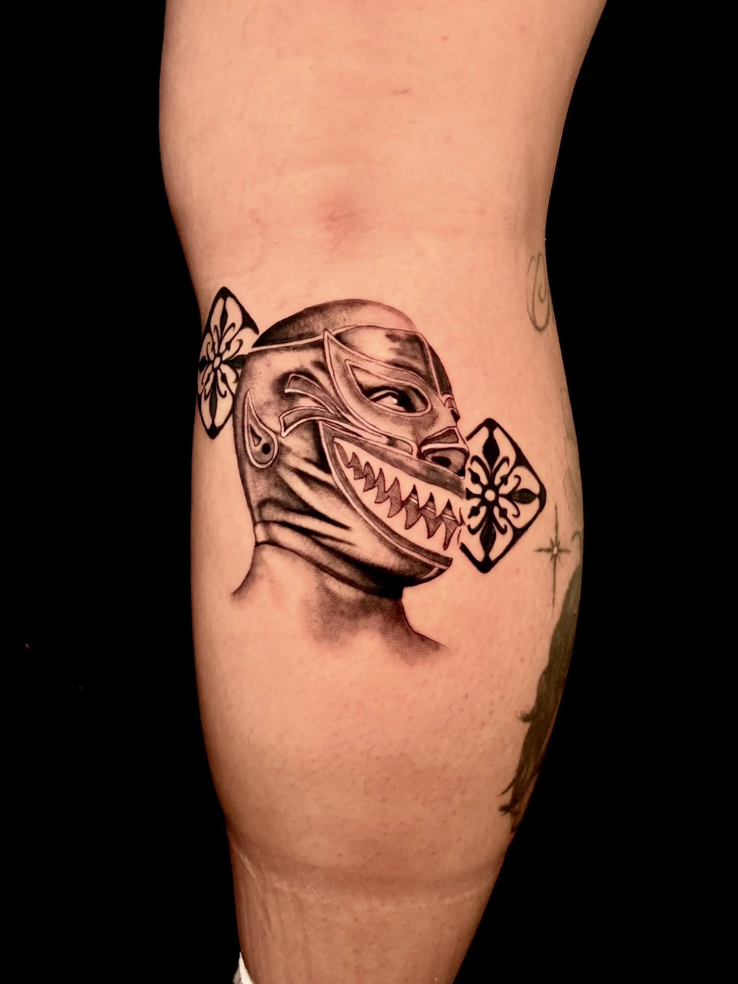 Tattoo of a wolf with a snarling expression on a person's arm, surrounded by decorative floral patterns.