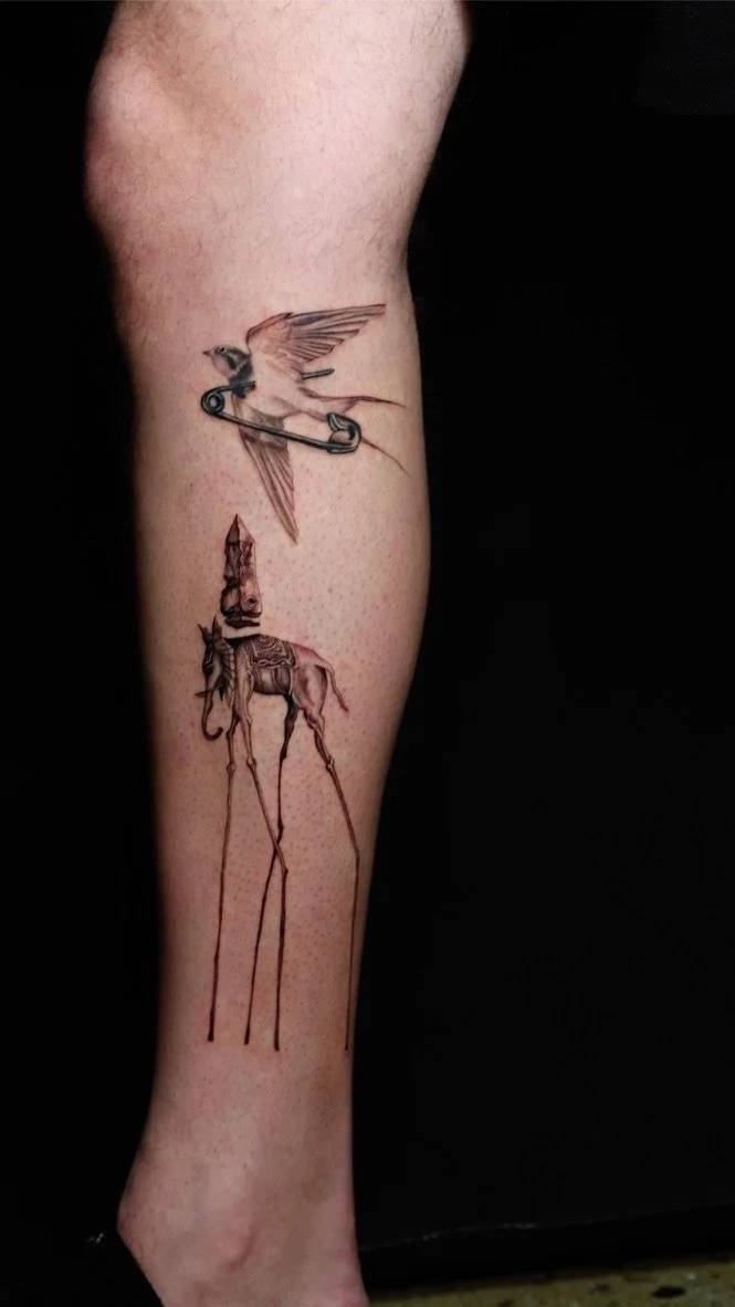 Tattoo of a bird flying with a safety pin as part of its body above a tall, thin, fantasy-style creature with a trumpet-shaped head and elongated legs.