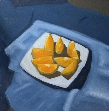 A small white plate with sliced orange pieces on a blue cloth surface.
