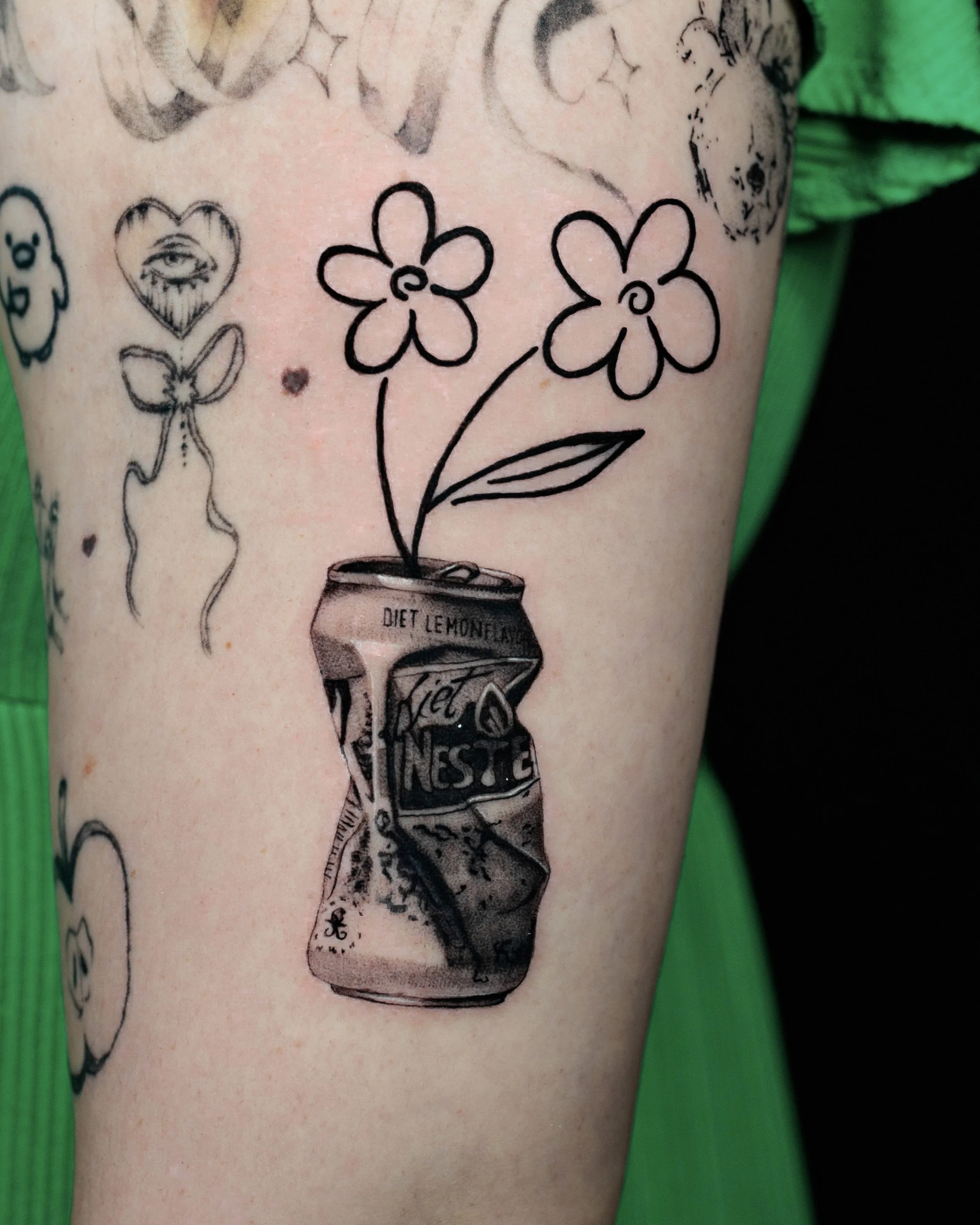 Tattoo of a soda can with a flower growing out of it, featuring the words "Diet Lemon" and some smaller, less legible text.