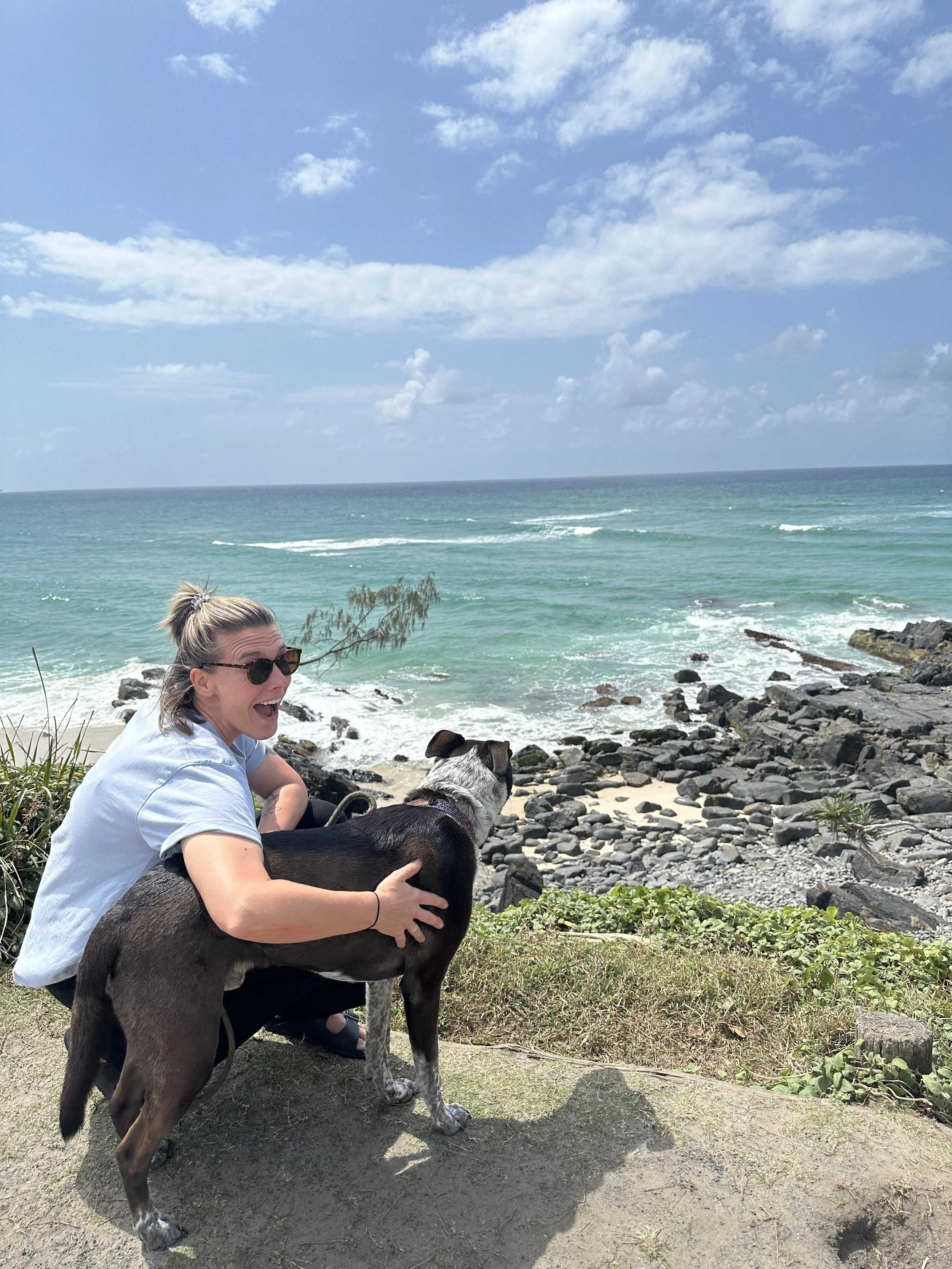 Chris and her dog Ripley sitting on the edge of a cliff looking at the ocean.