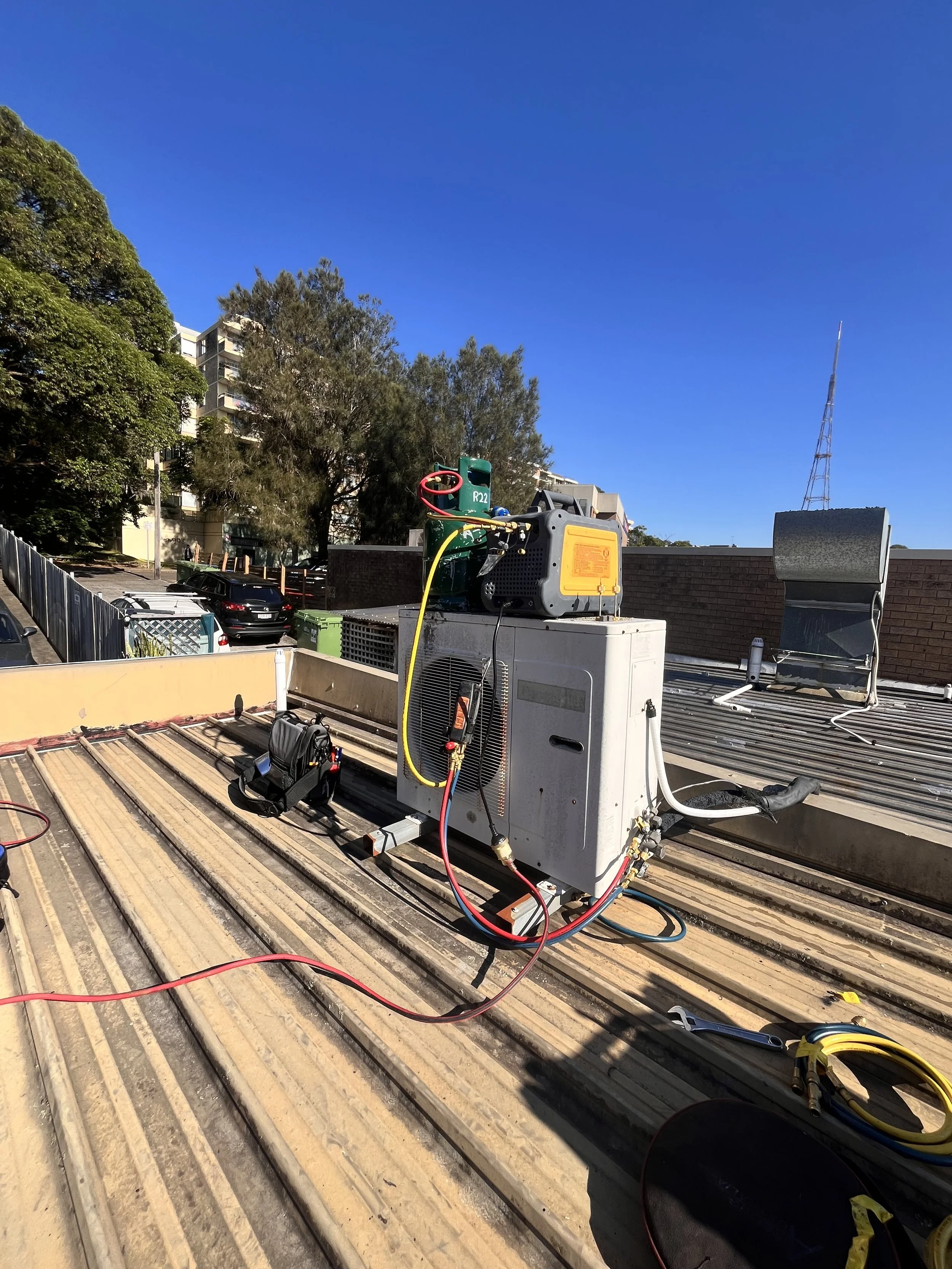 Refrigerant recovery gear connected to an outdoor unit on a metal roof
