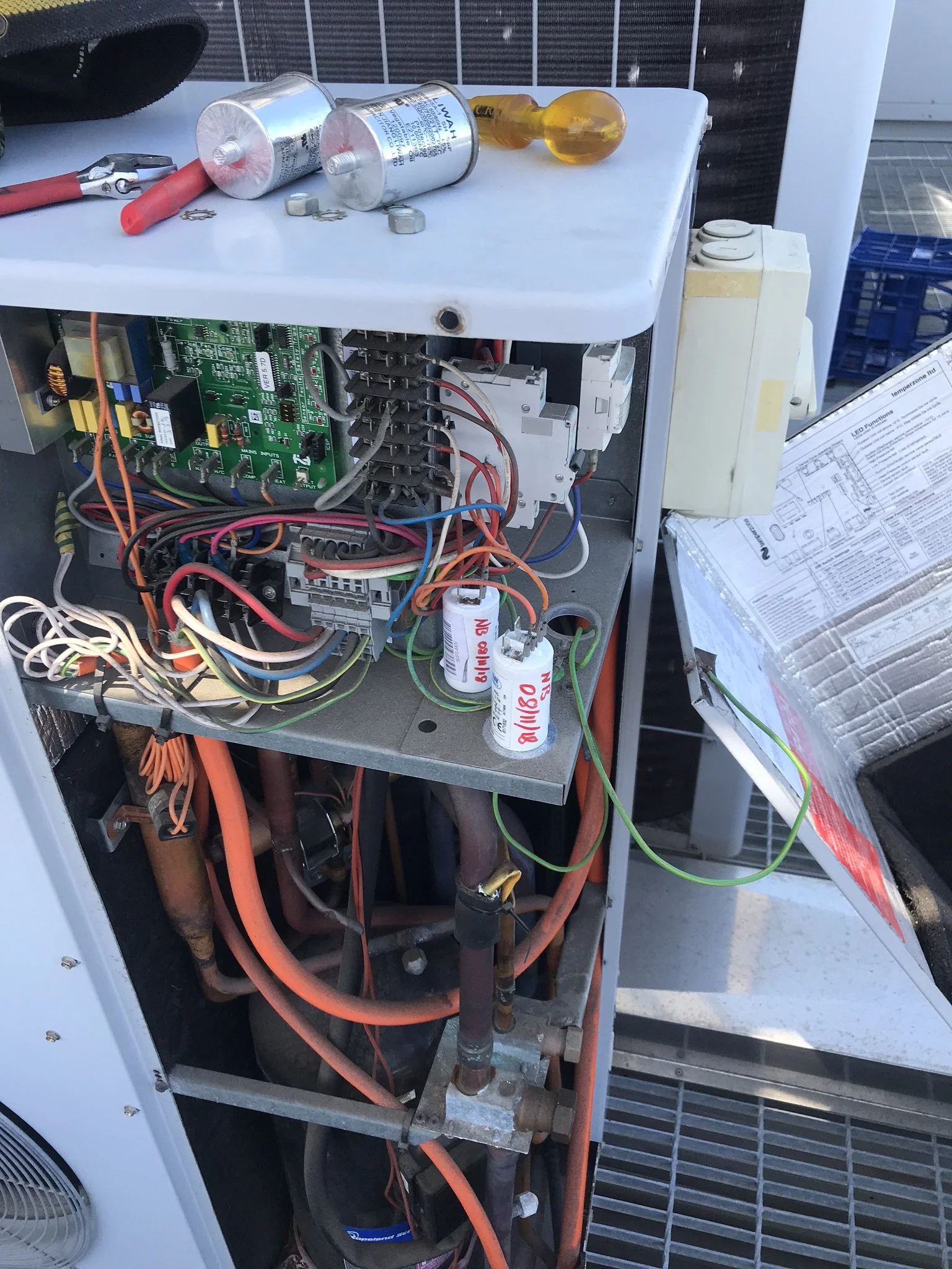 Outdoor air conditioning unit opened up for repair, with the control board and wiring exposed