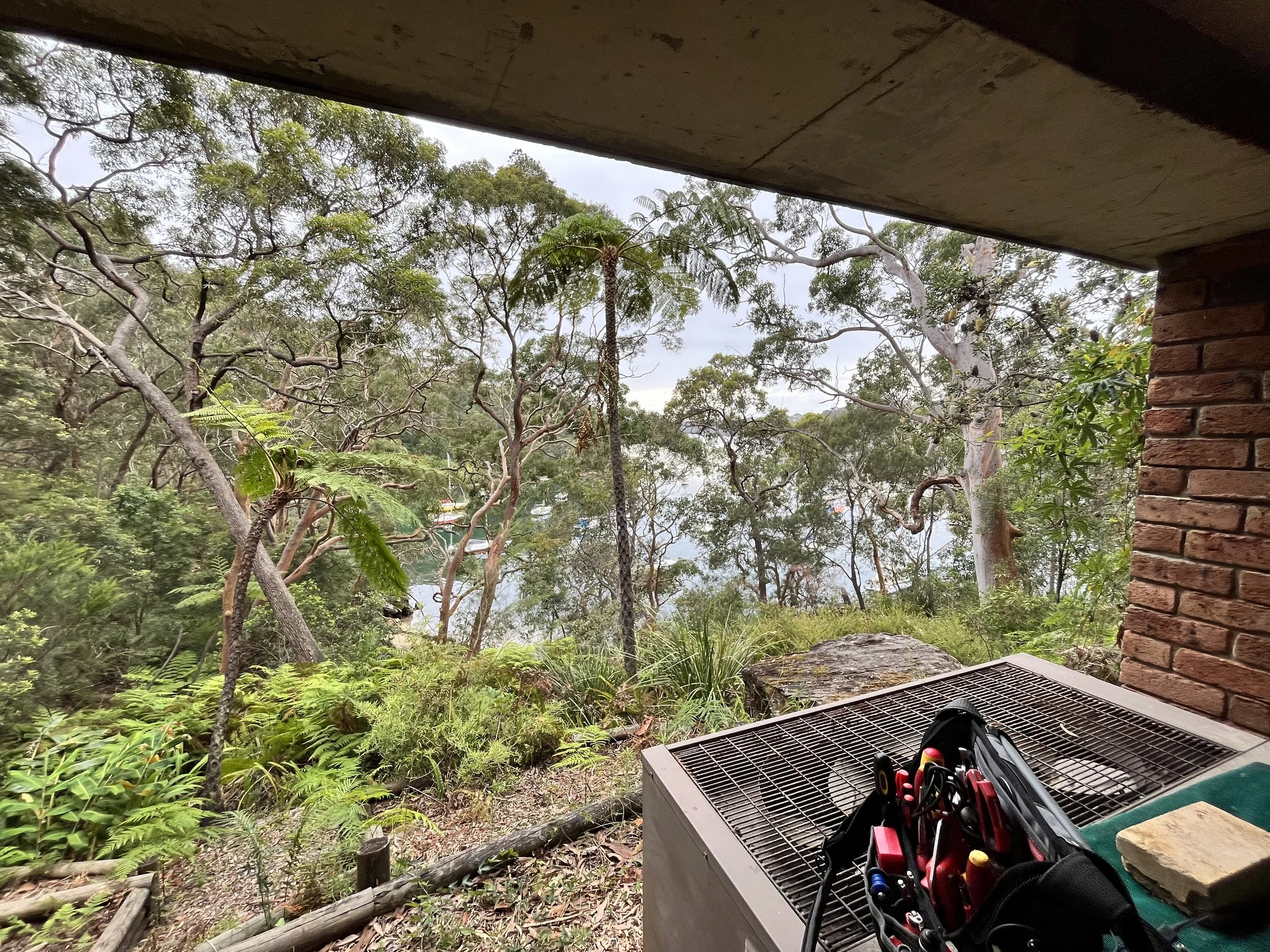 Tools on a package unit under a house overlooking bushland