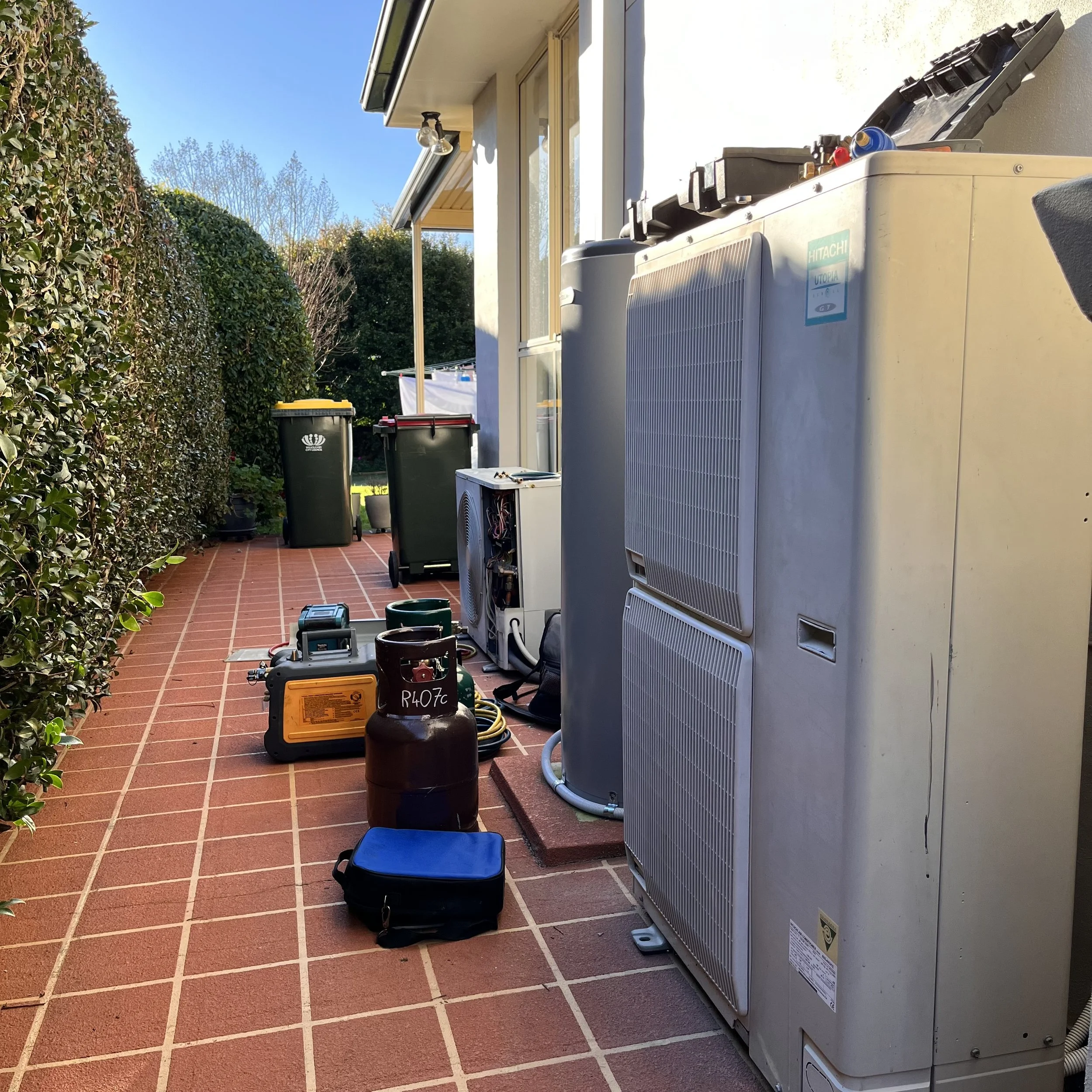 Refrigerant recovery equipment set up beside two outdoor air conditioning units