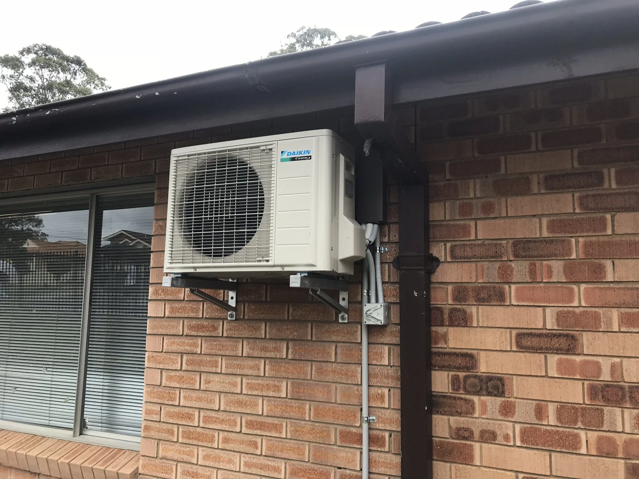 Split system outdoor unit on wall brackets on a brick house