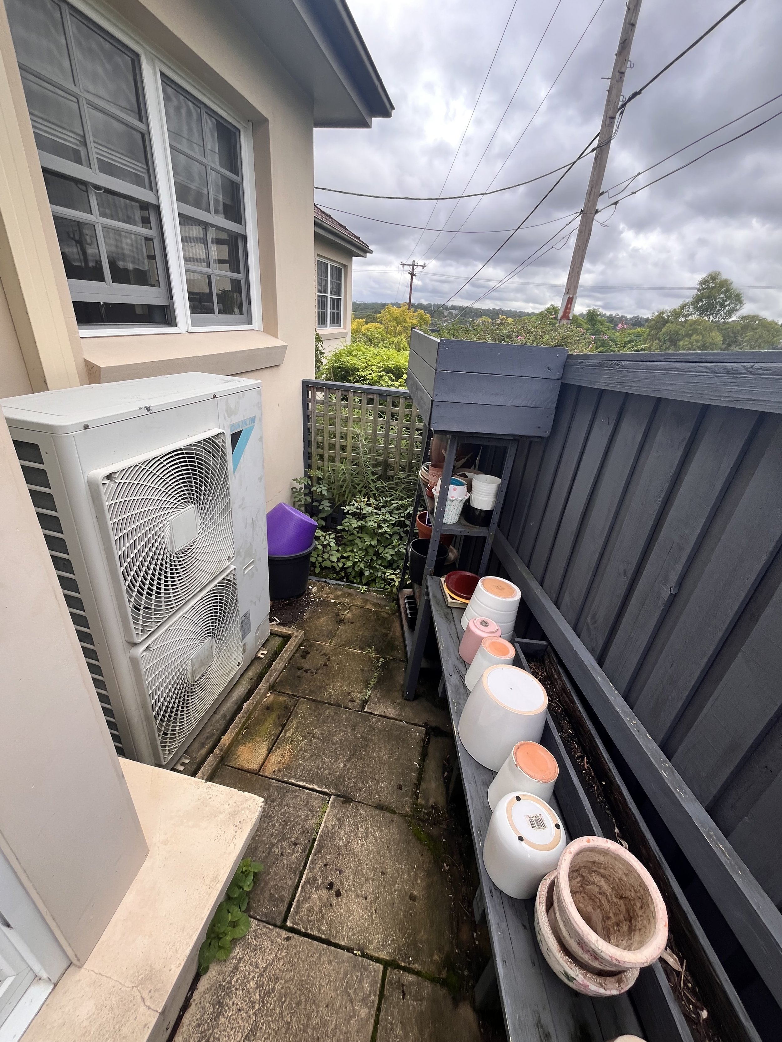 Ducted air conditioning outdoor unit along the side of a house