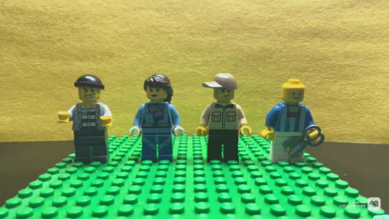 Four LEGO minifigures standing on a green LEGO baseplate against a yellow background.