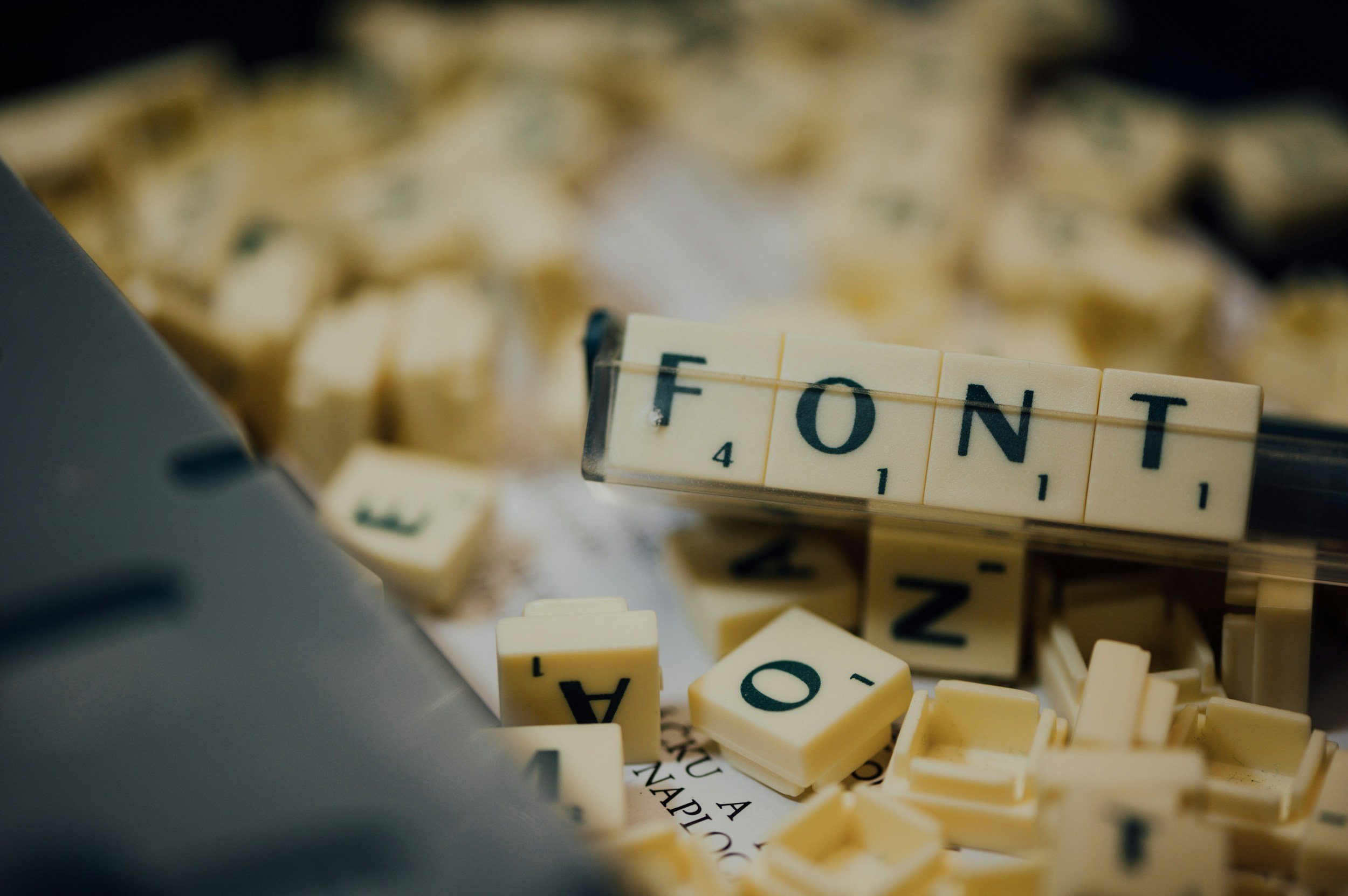 Close-up of Scrabble game pieces scattered, with the word 'FONT' visible on one tile.