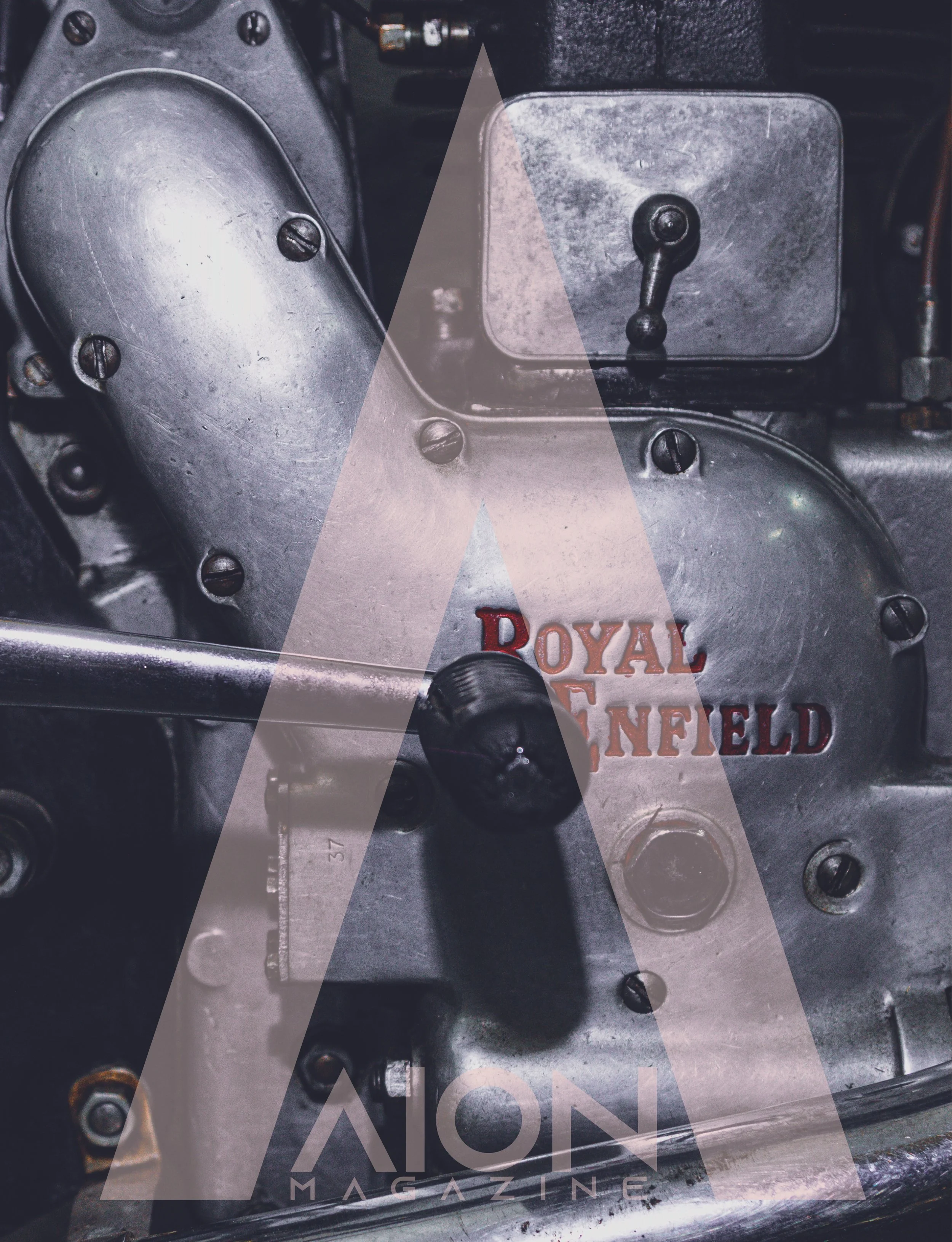 Close-up of a vintage engine part with visible screws, a lever, and a logo reading 'Royal Enfield' on a metallic surface, overlaid with a transparent 'A' logo from 'Aston Magazine'