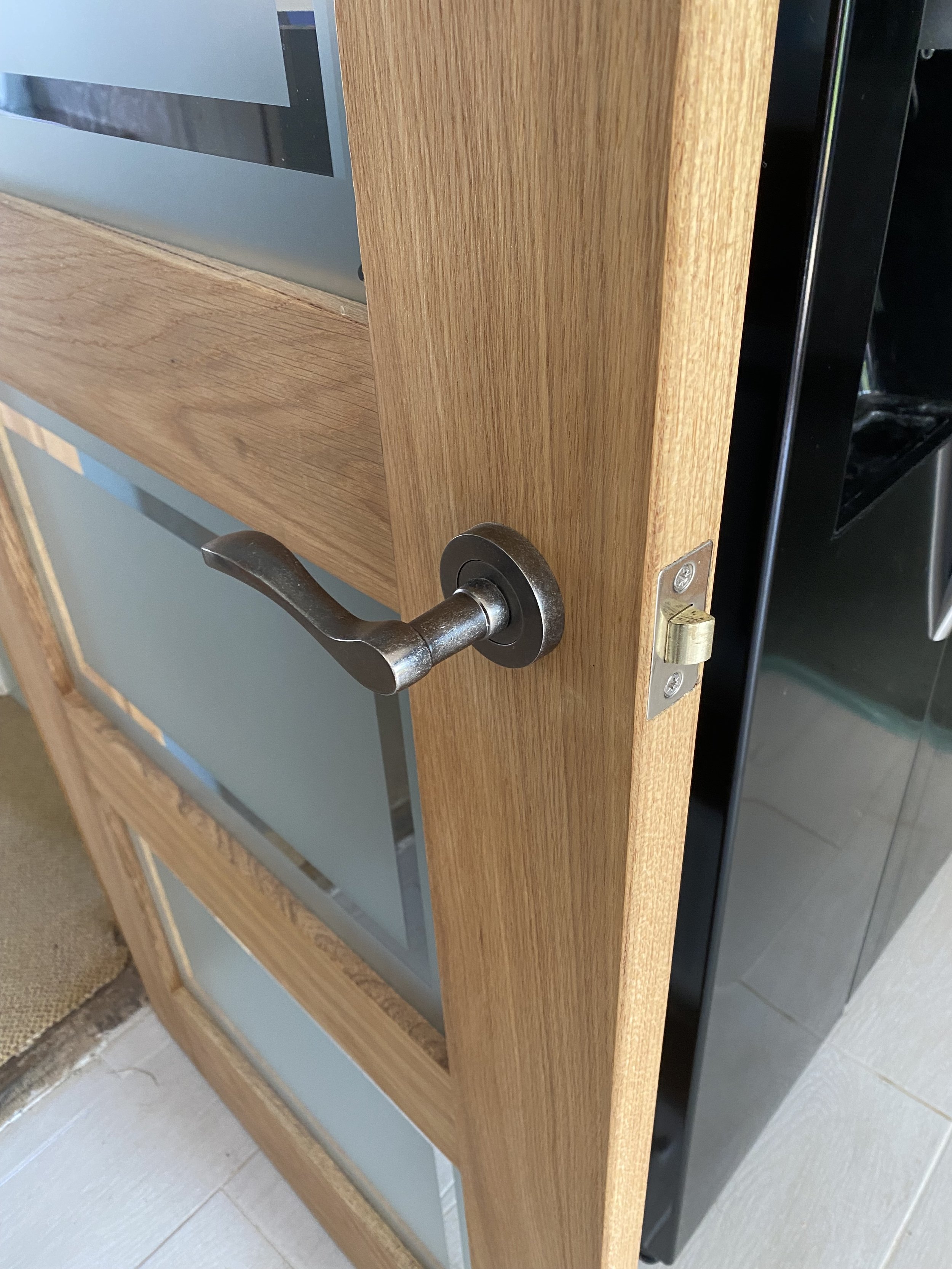 Close-up of a partially open wooden door with a dark metal lever handle and visible latch.