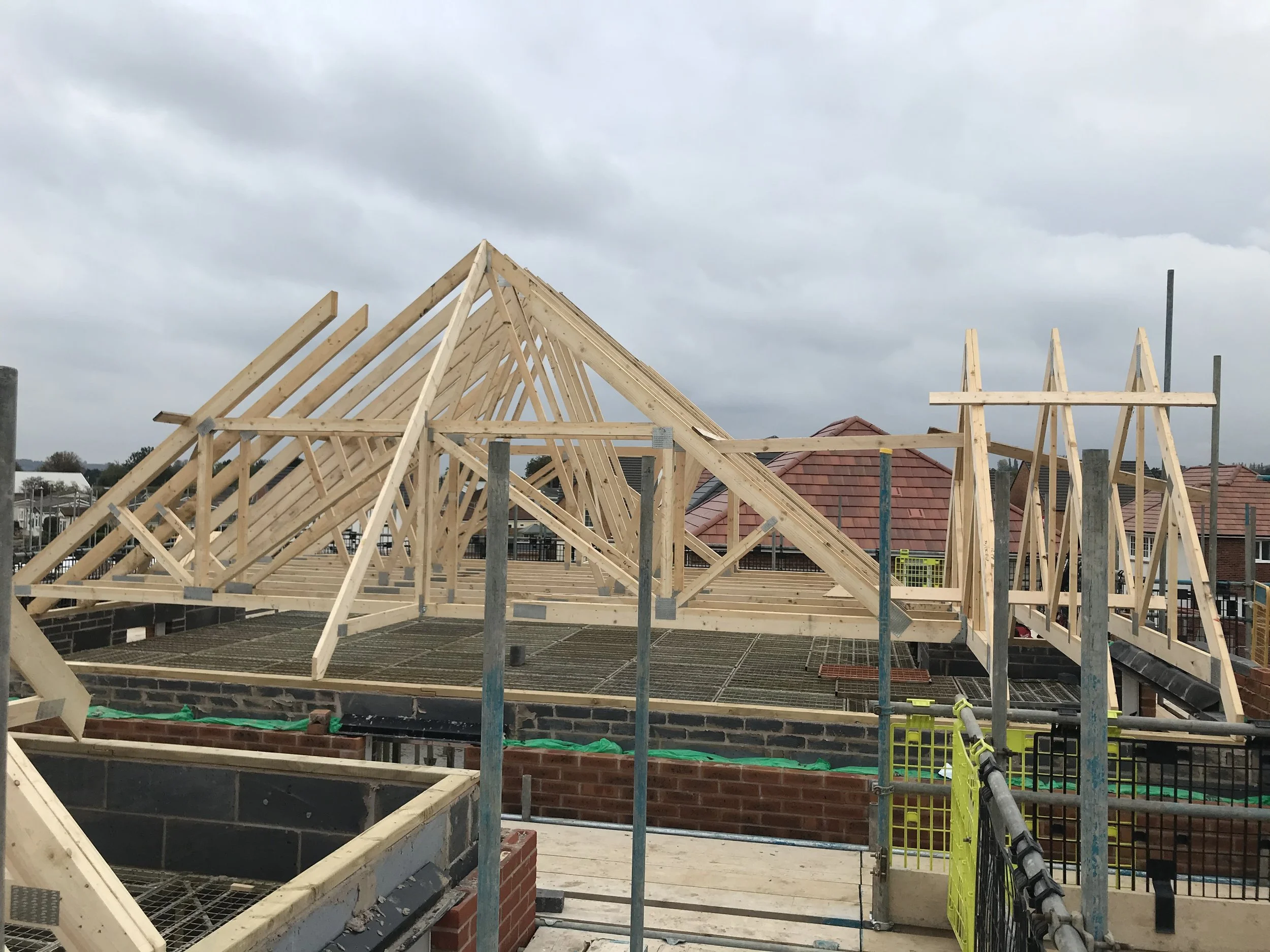 Wooden roof trusses being installed on a brick house under construction