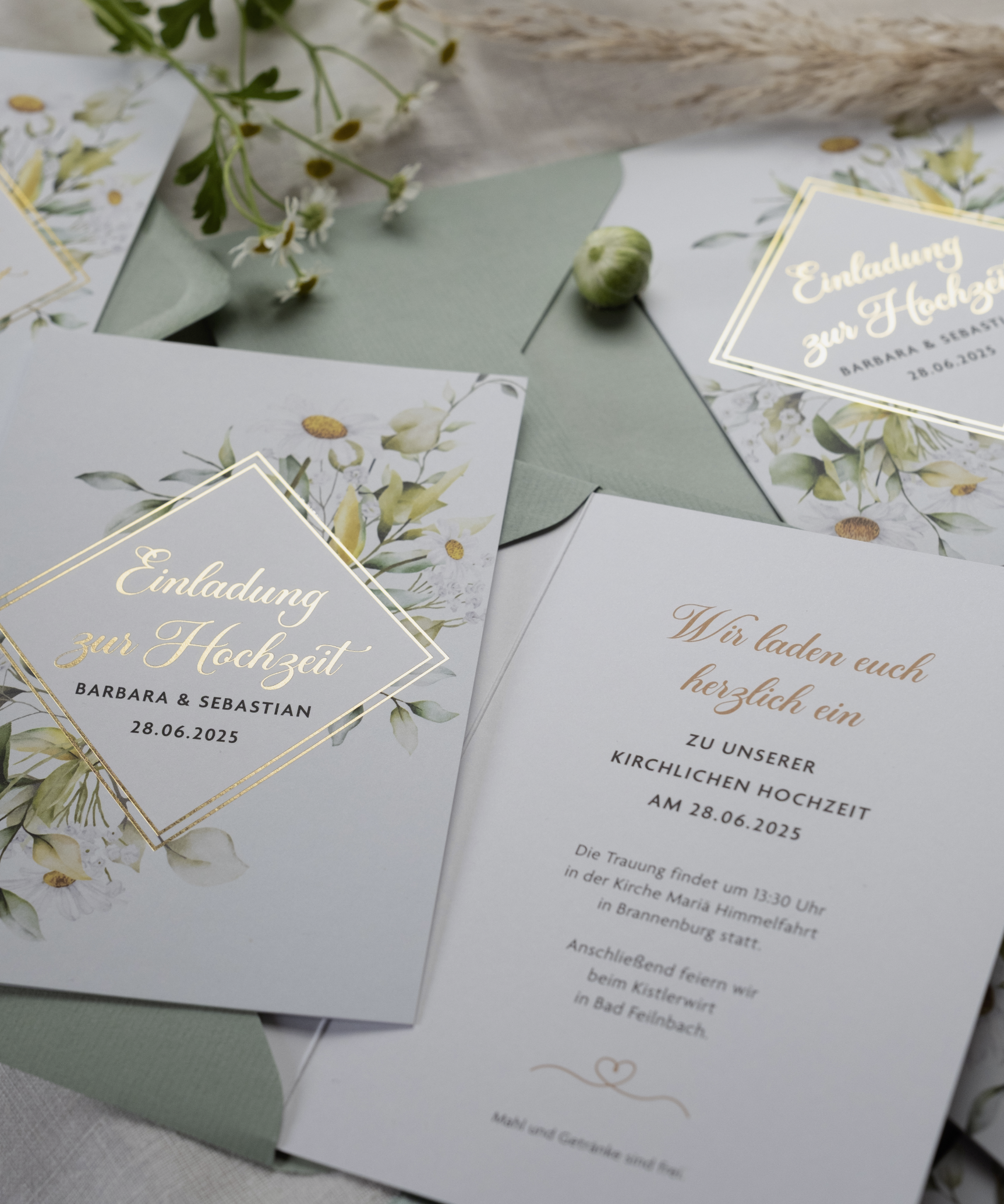 Einladungskarten für eine Hochzeit mit floralem Design und goldener Schrift und Dankeskarte in passendem Design.