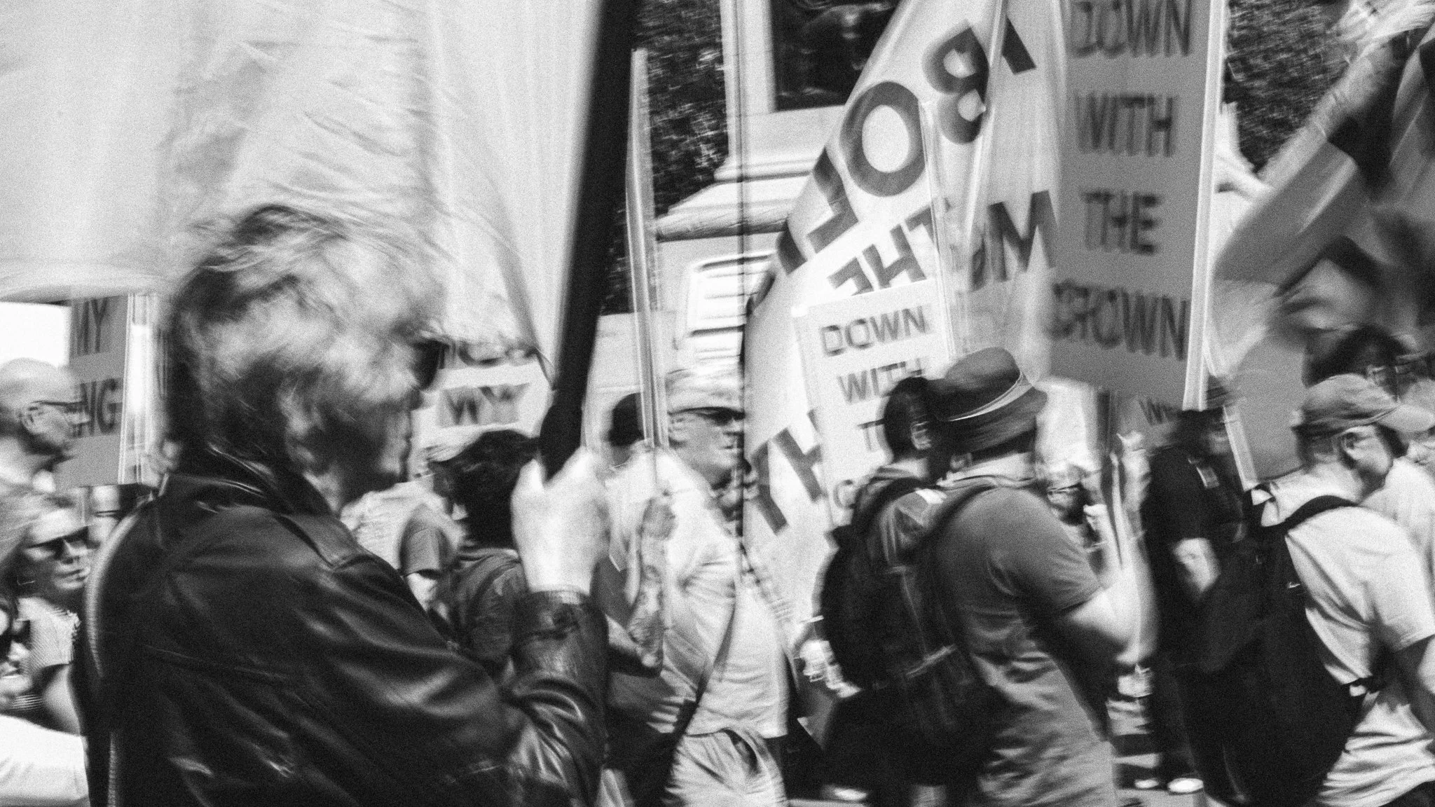 A black and white photo of people participating in a protest or march, holding signs and banners supporting workers' rights.