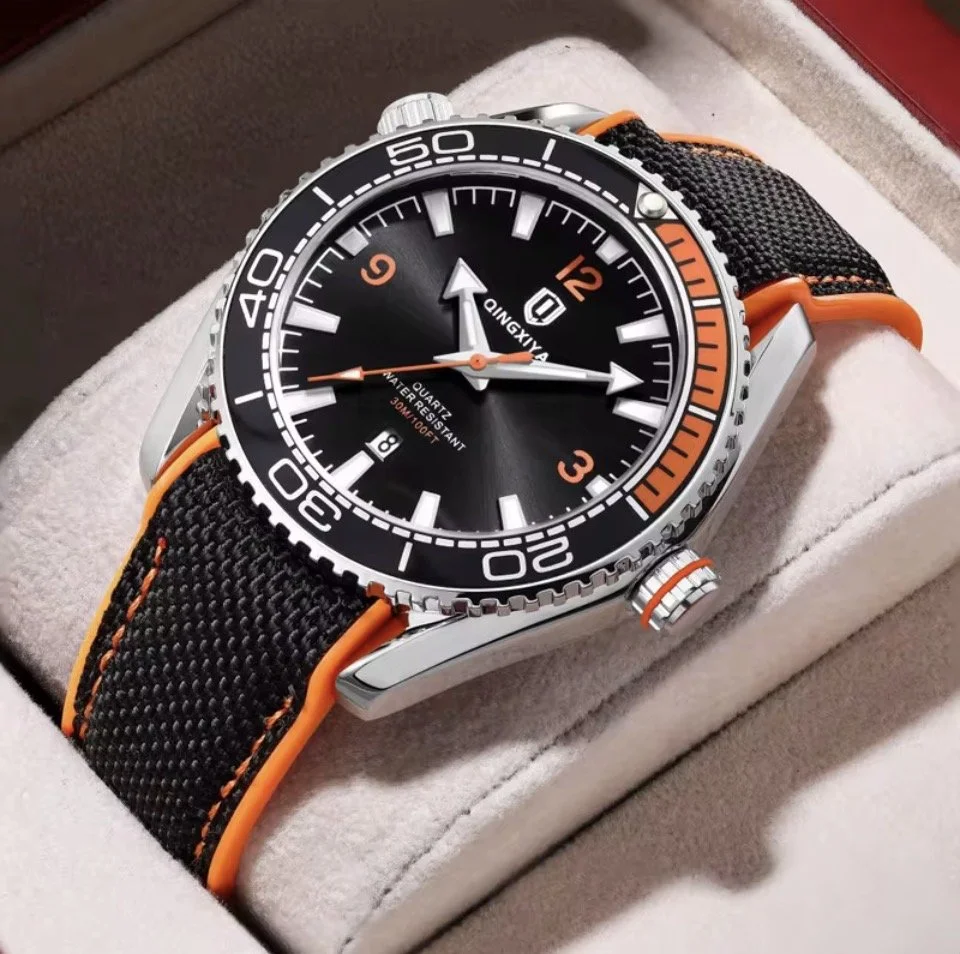 A black and orange wristwatch with a round dial and a fabric strap, resting on a soft cushioned surface.