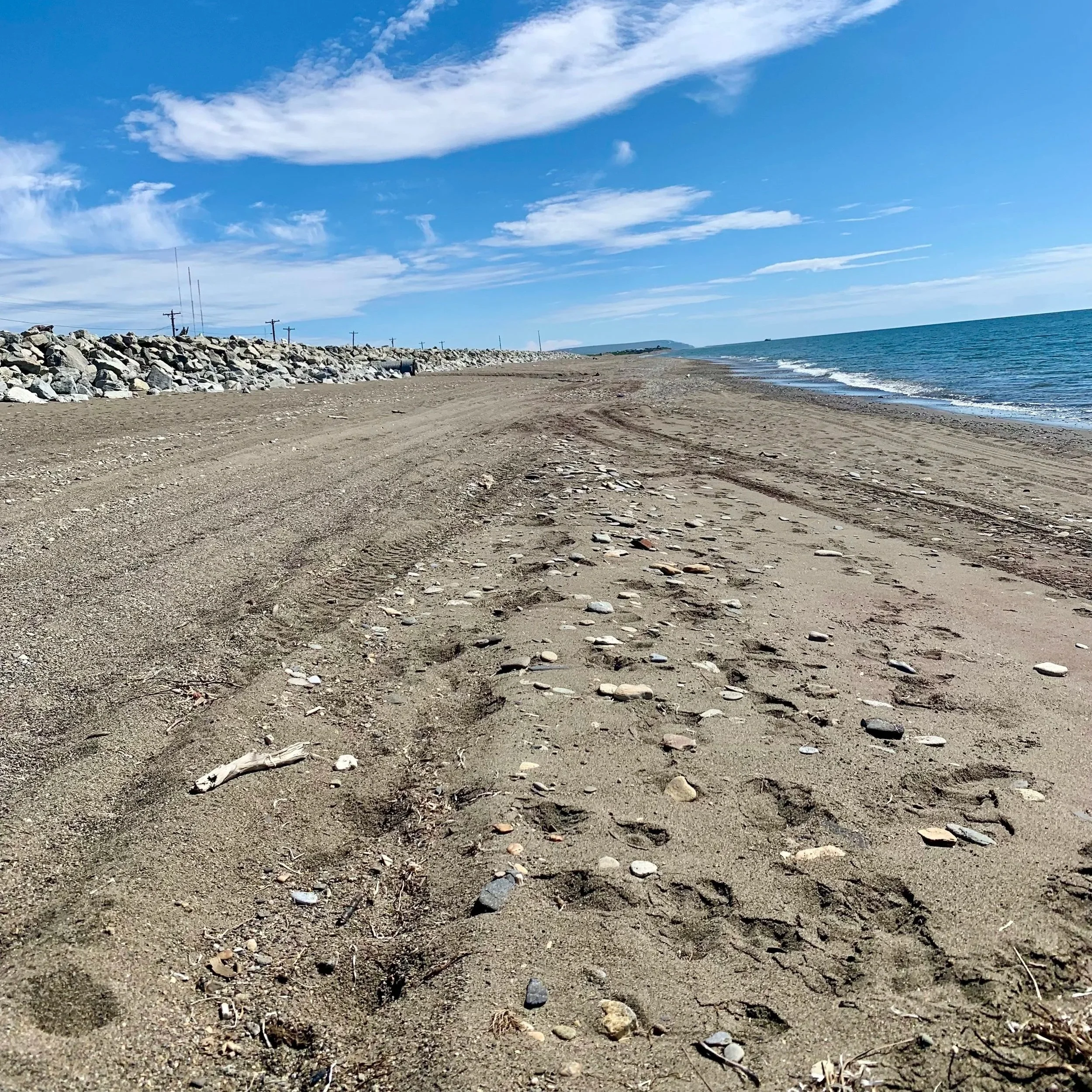 A sea glass hunting beach in Nome, Alaska, bordered by a rocky breakwater.