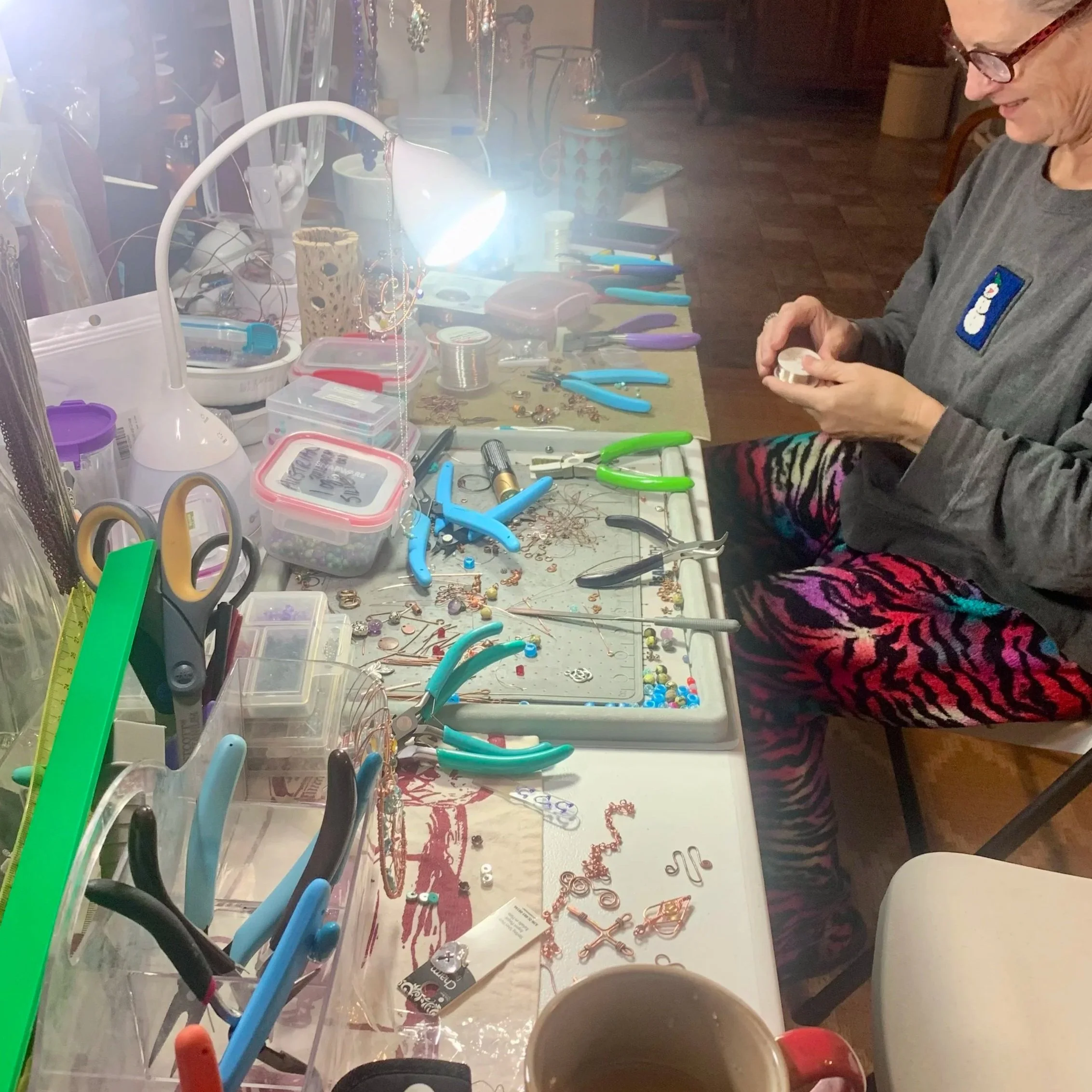 Terrie working at her jewelry crafting station, surrounded by pliers, wire, and beads.