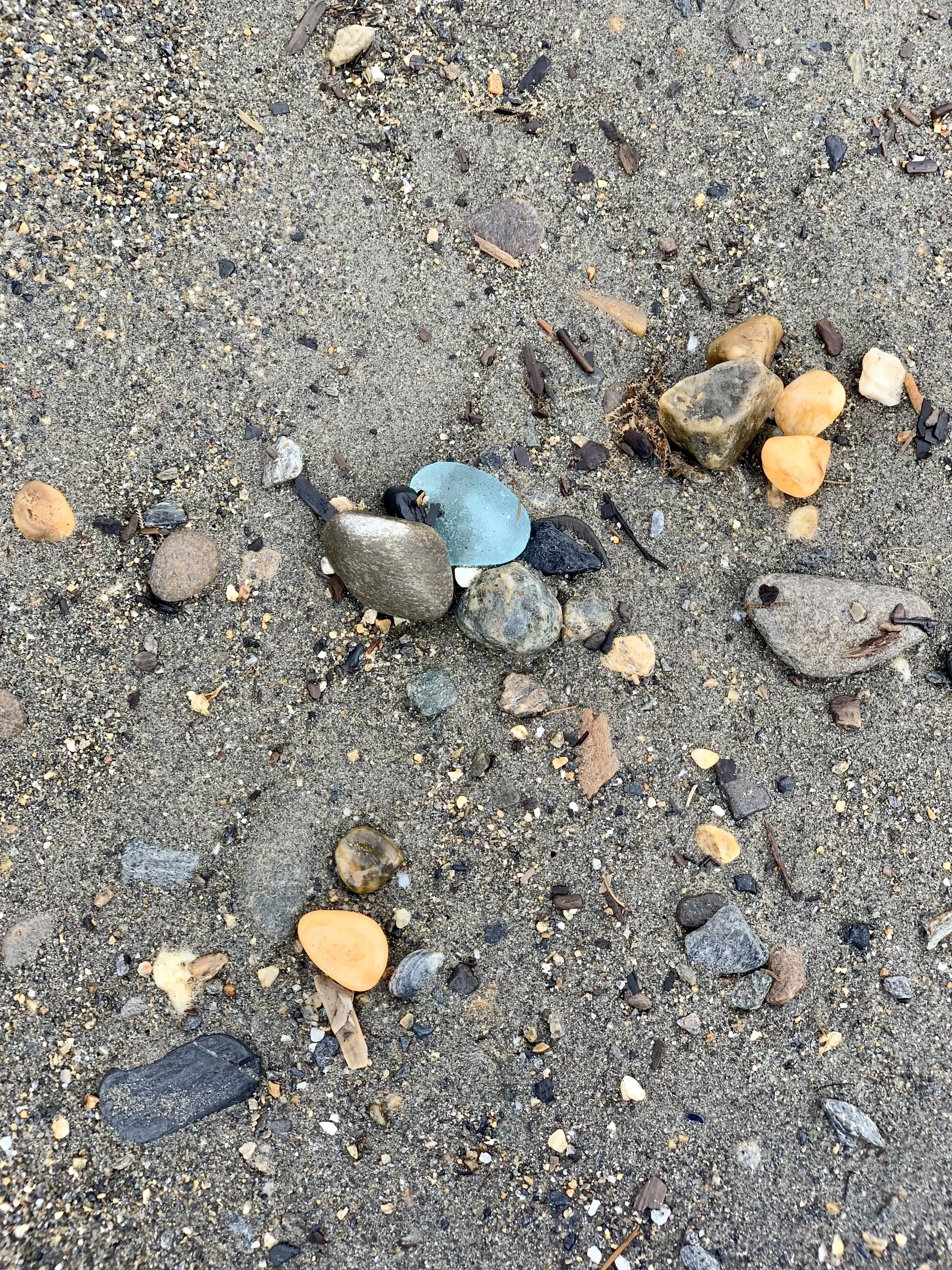 A sea glass hunting beach in Nome, Alaska, with driftwood scattered among the rocks and pebbles.