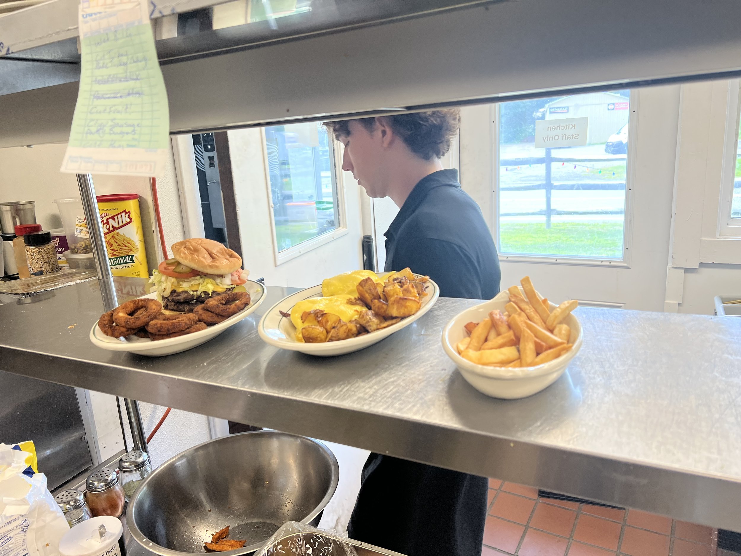 Cook plating burgers, fried chicken, onion rings and fries in the Royal Diner kitchen, West Brattleboro VT