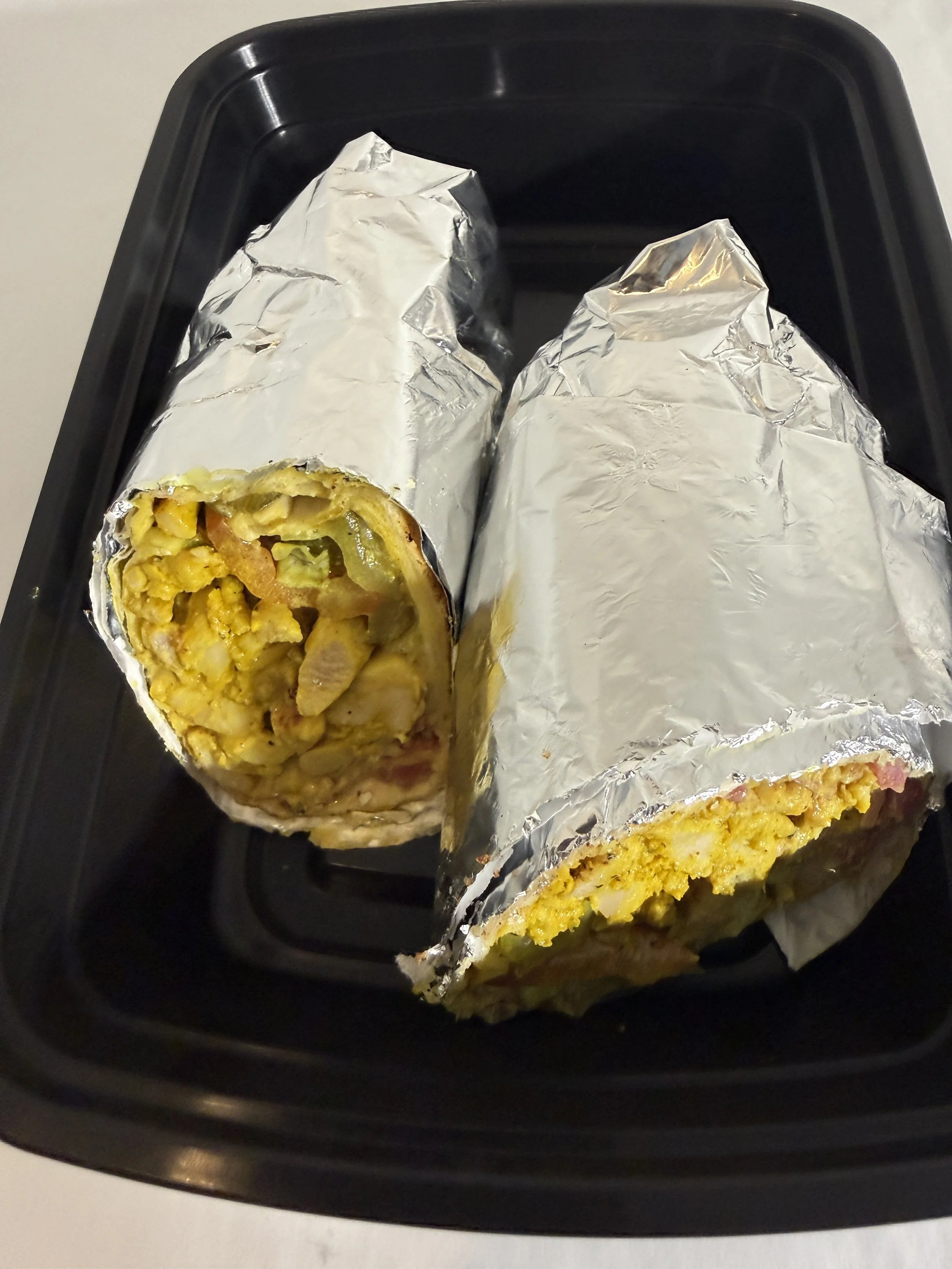 Two breakfast burritos with scrambled eggs in a takeout container from Royal Diner