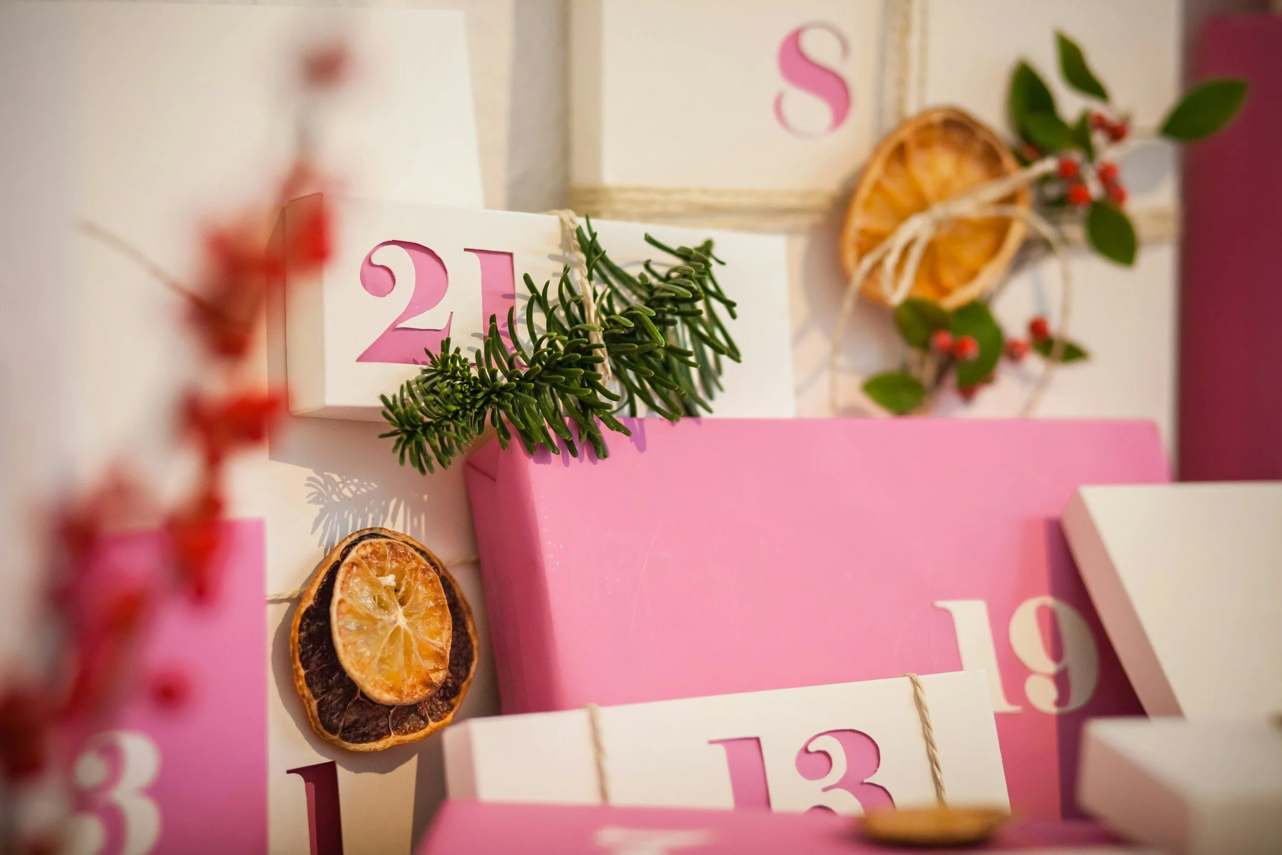 Nächtliche Adventskalender mit pinken Zahlen, getrocknete Orangenscheiben, grüne Herzkiefernzweige und rote Beeren