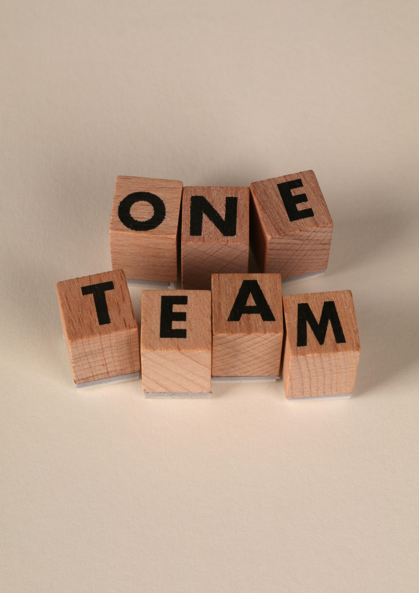 Wooden blocks spelling out 'ONE TEAM' against a plain background.