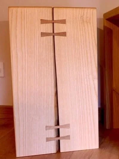 Une porte en bois avec un design unique, comprenant des encoches horizontales en haut et en bas.