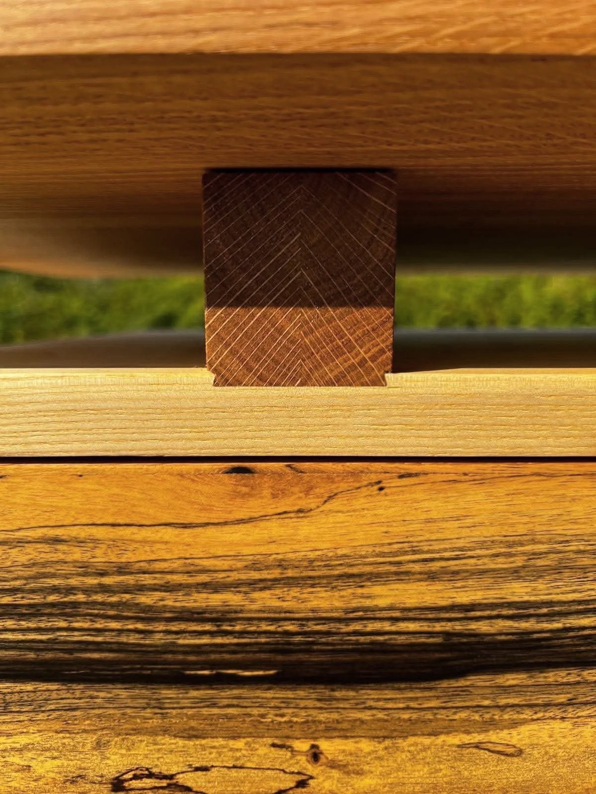 Une image prise en plongée montrant un assemblage de blocs de bois différents, notamment un bloc de bois sombre au centre, inséré entre deux autres blocs de bois clair et foncé.