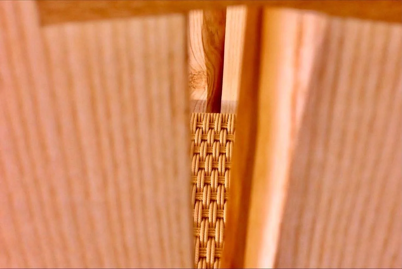 Photo prise à travers un espace étroit entre deux surfaces en bois, montrant une corde tressée en dessous.