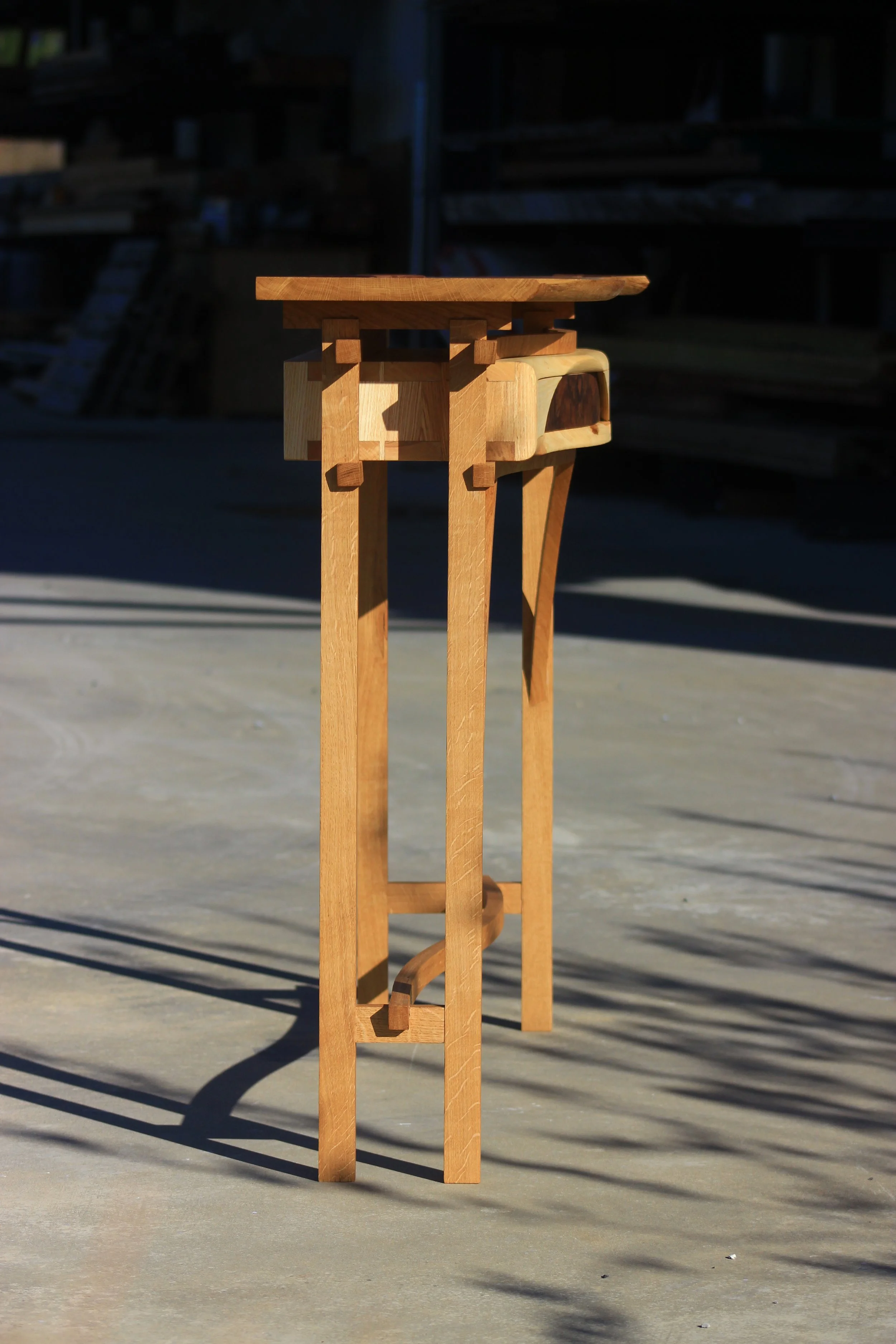 Une petite table en bois dans un espace semi-extérieur avec un fond sombre.