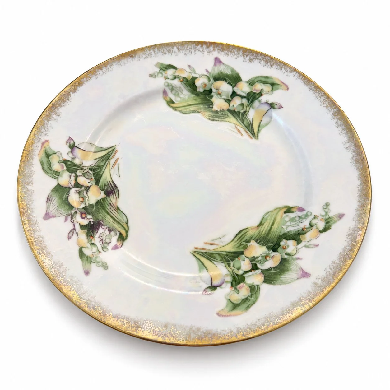 Angled view of the lily-of-the-valley plate showing its lustrous surface.