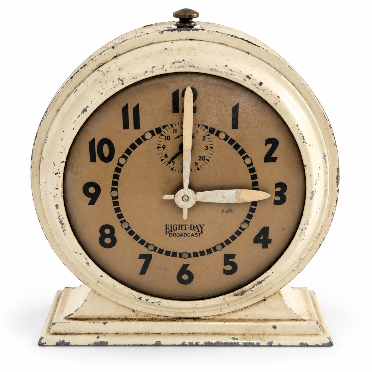 Angled view of the cream metal Broadcast clock showing its round case and stepped pedestal base.