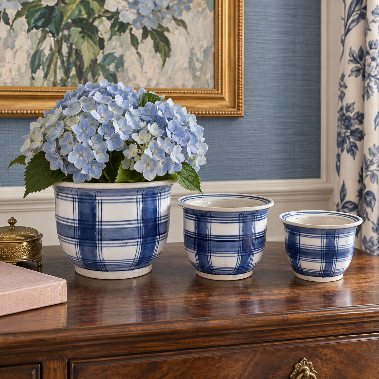 Blue-and-white plaid planters styled with white hydrangeas and greenery in a sunroom.