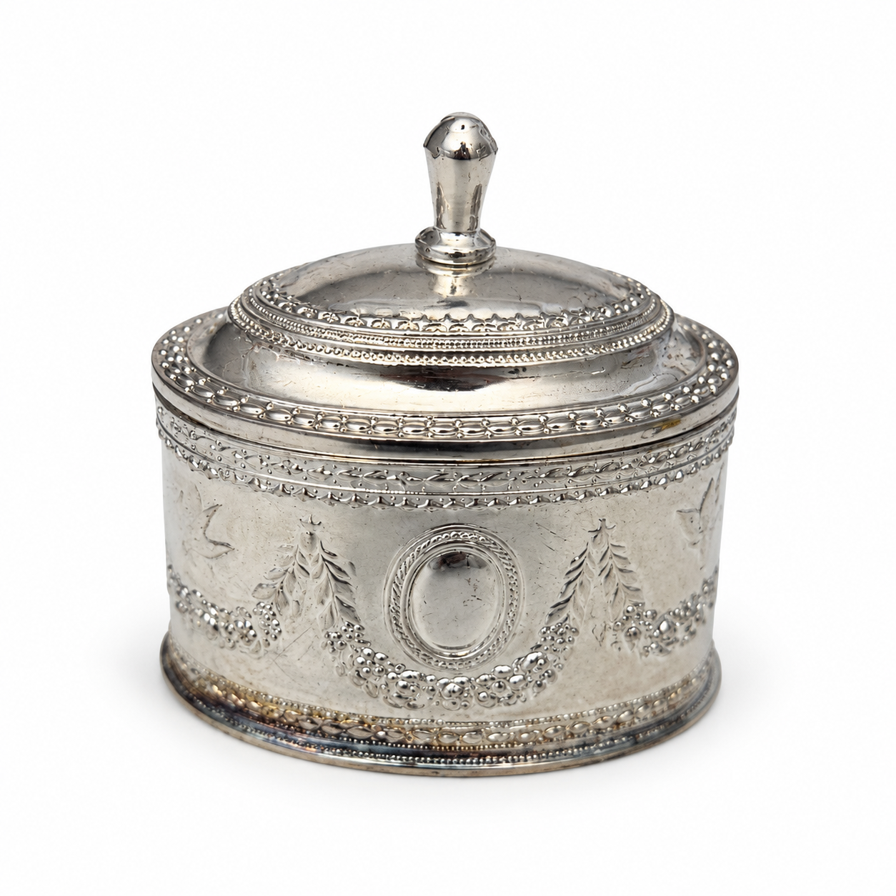Oval silver-tone trinket box beside a tape measure showing its height including the lid knob.