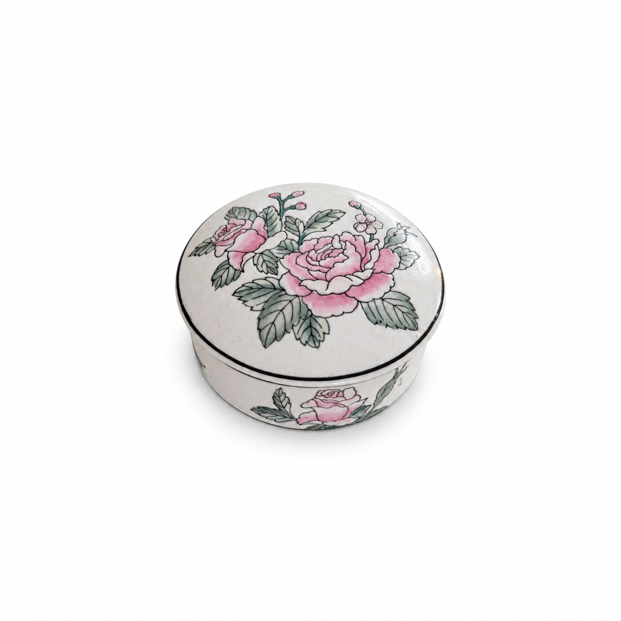 Round Chinese porcelain trinket box with pink flowers, green leaves and black edging on a white background.