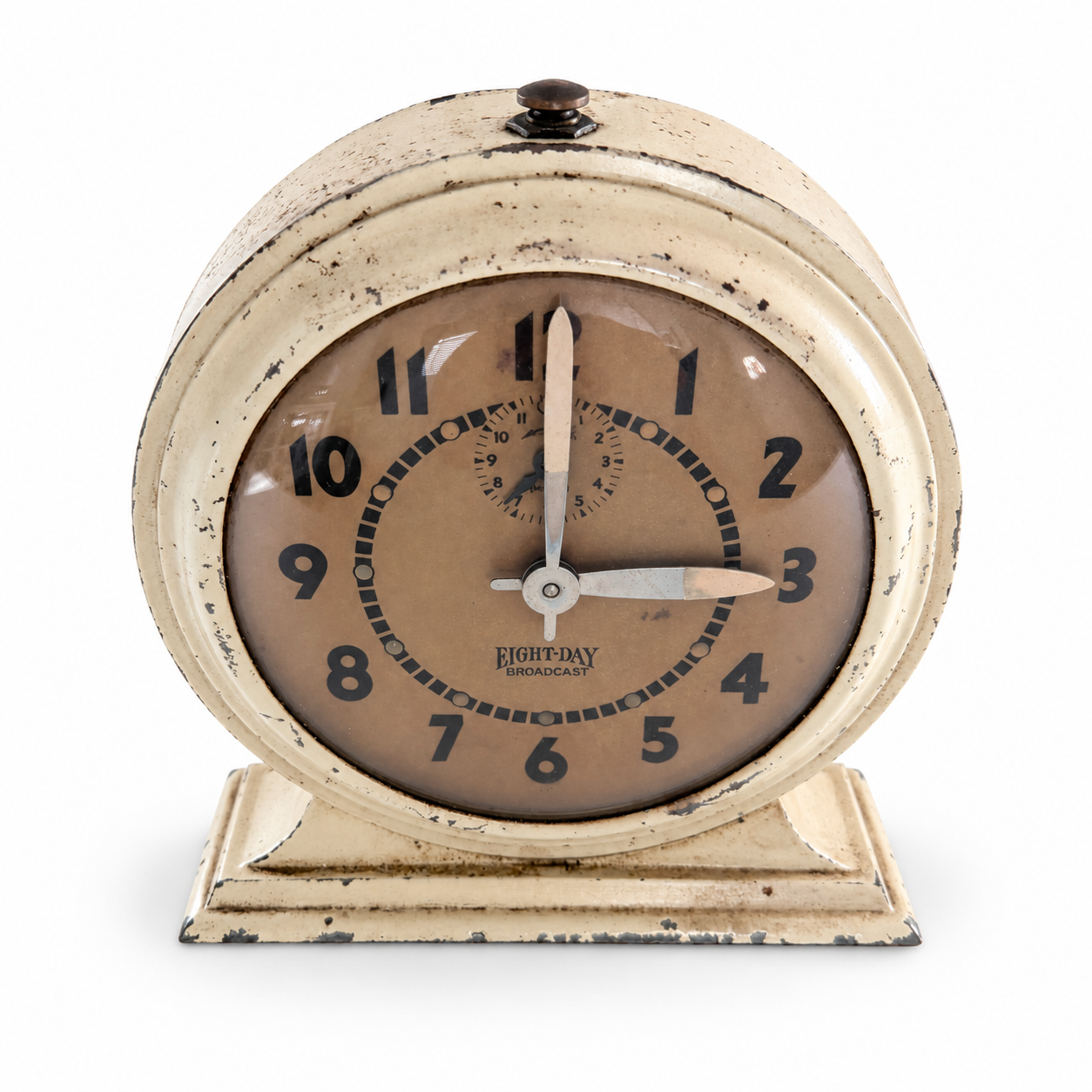Close view of the Broadcast clock’s aged dial and cream pedestal in a colorful study setting.