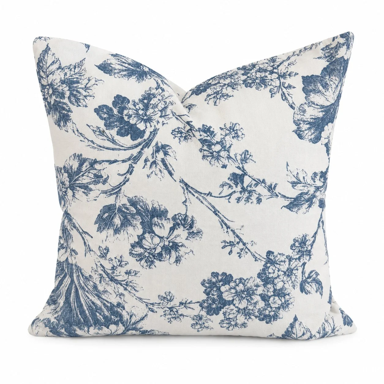 Blue and ivory botanical pillow on an upholstered bench beside a walnut table.